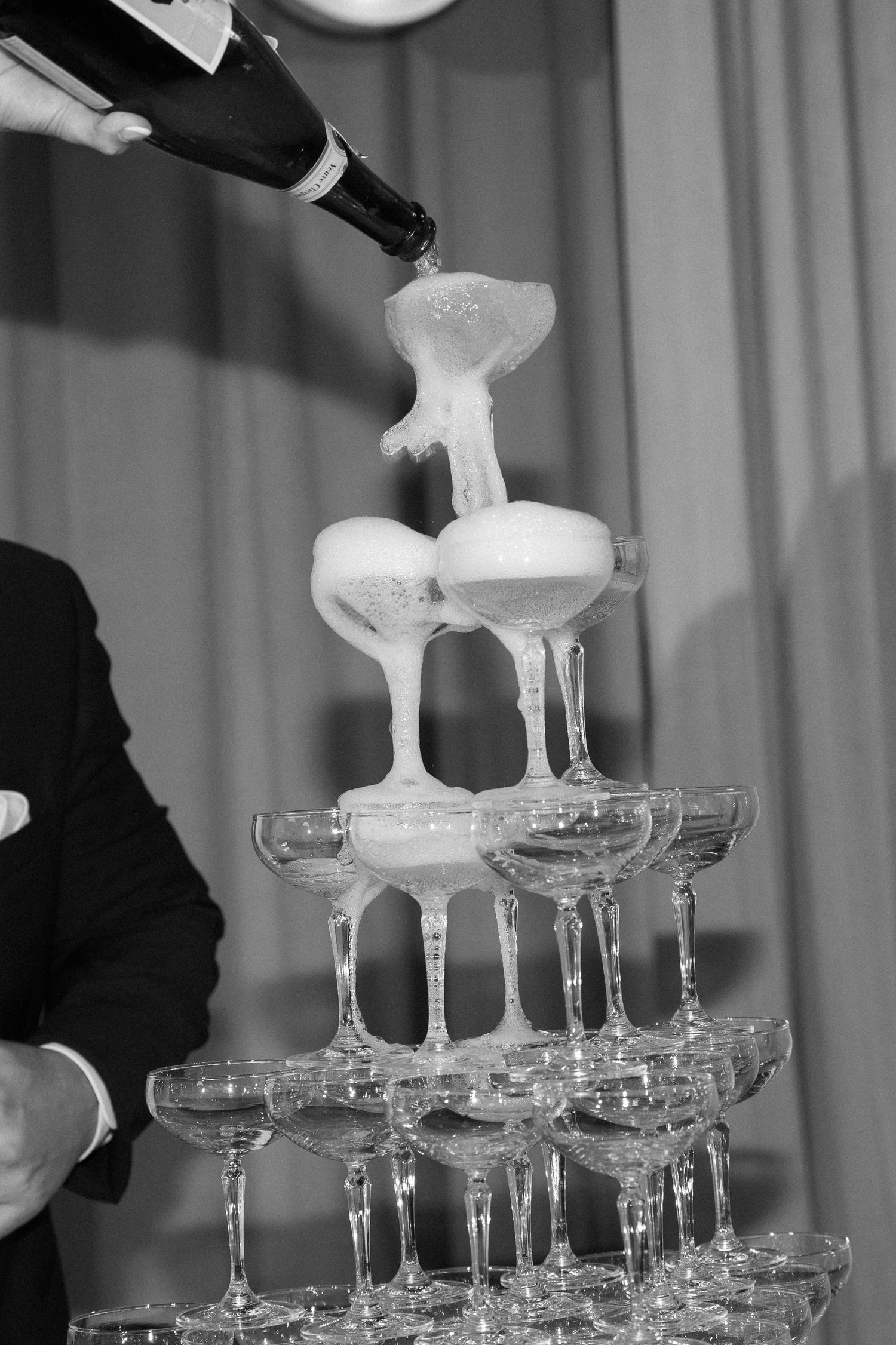 Champagne being poured into a tower of stacked crystal glasses creating an elegant cascade effect at an event.