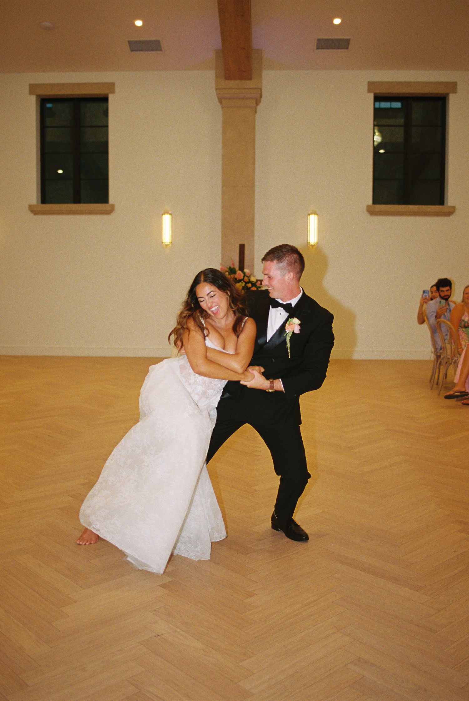 Bride and groom share a joyful first dance in an elegant ballroom during their wedding reception.