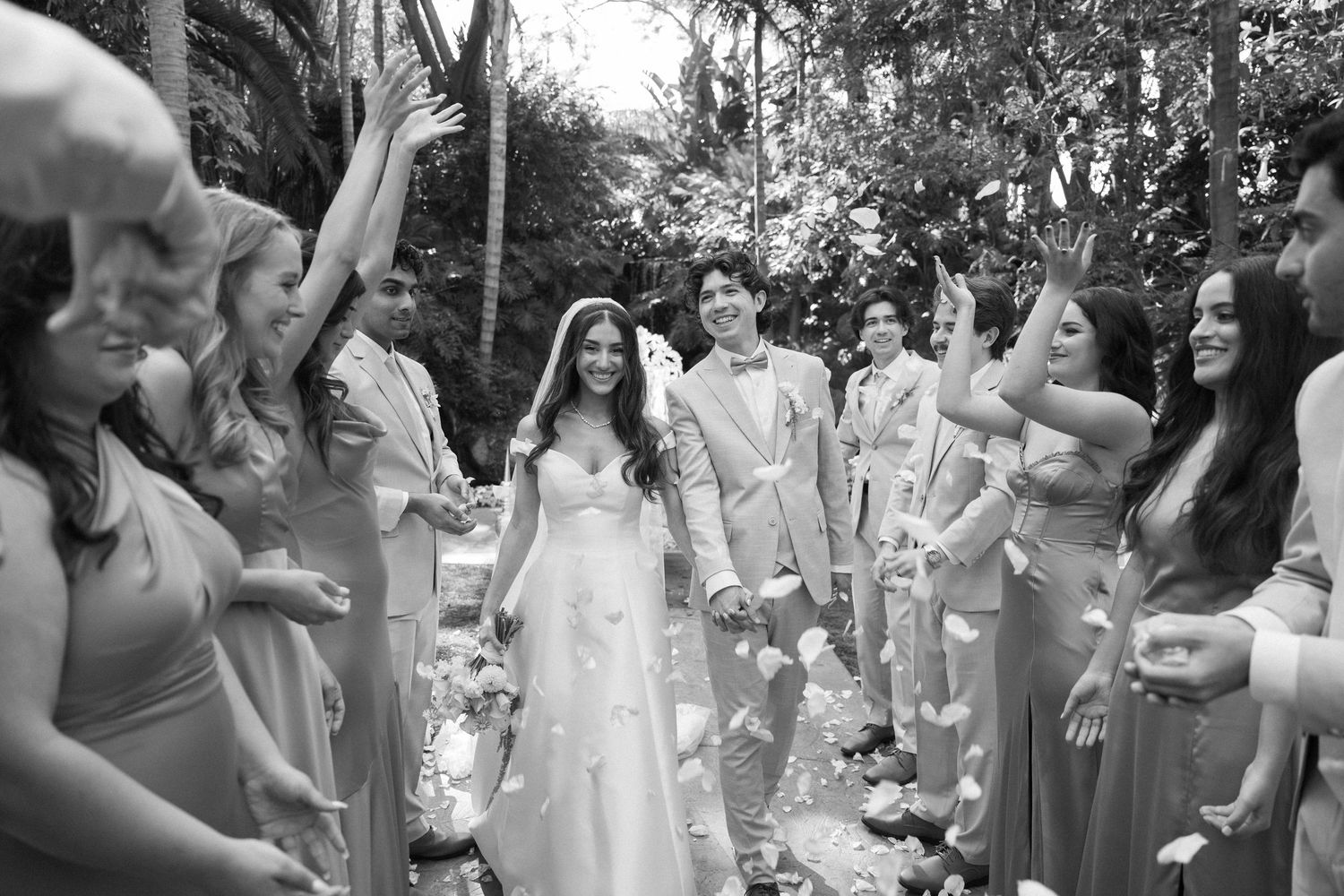 Wedding celebration with guests in white attire dancing and celebrating outdoors.