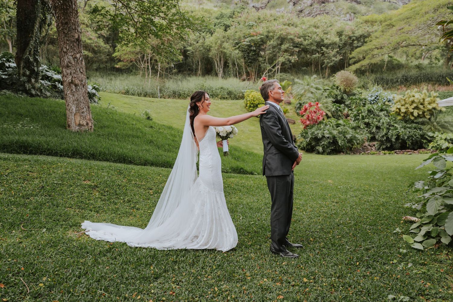 Couple sharing a romantic moment in a lush garden setting with mountains visible in the background.