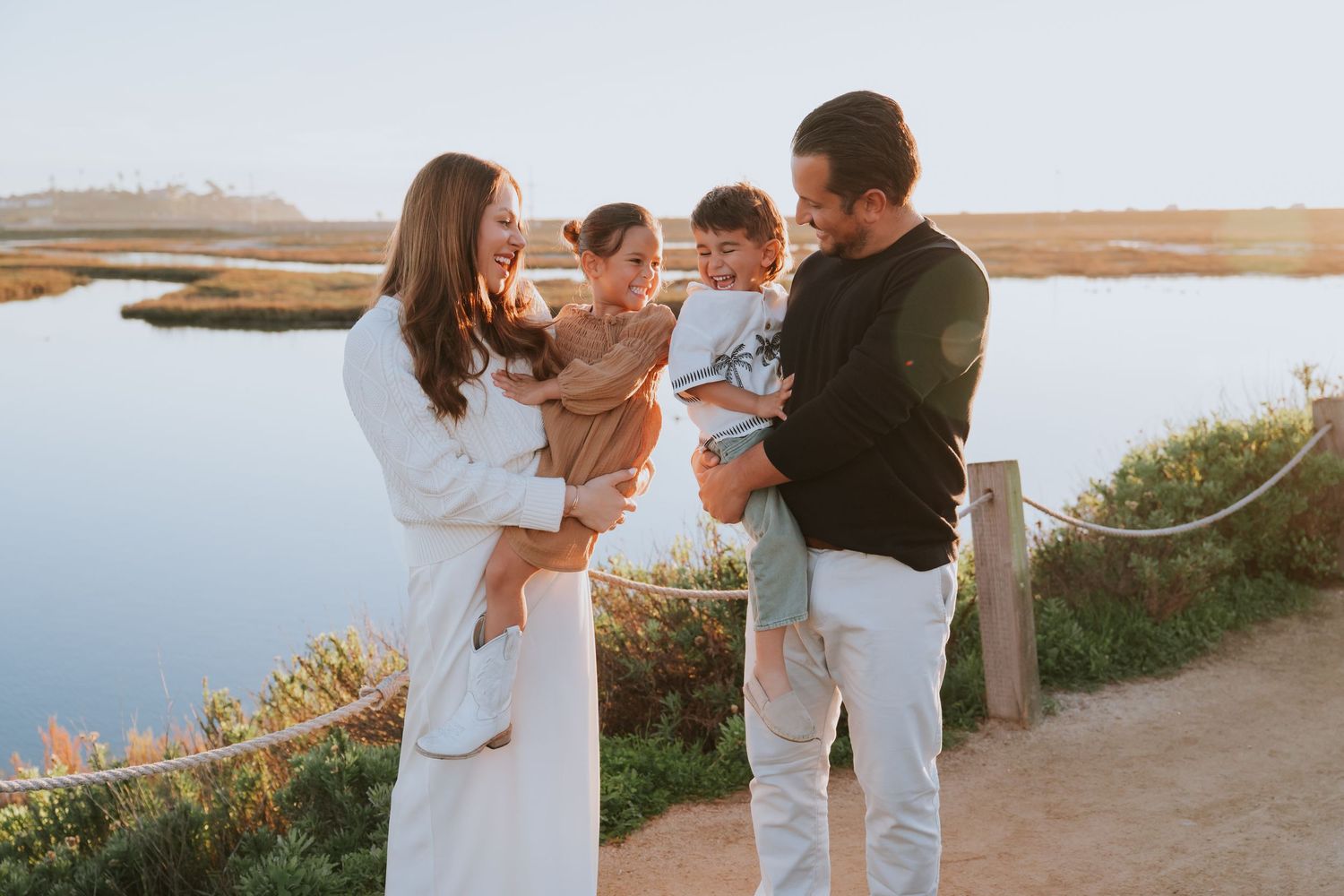 Wedding party enjoying a sunset moment on a coastal path with water views.