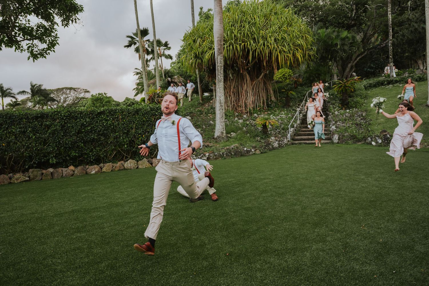 Wedding guests playing outdoor lawn games at a tropical garden venue with palm trees.