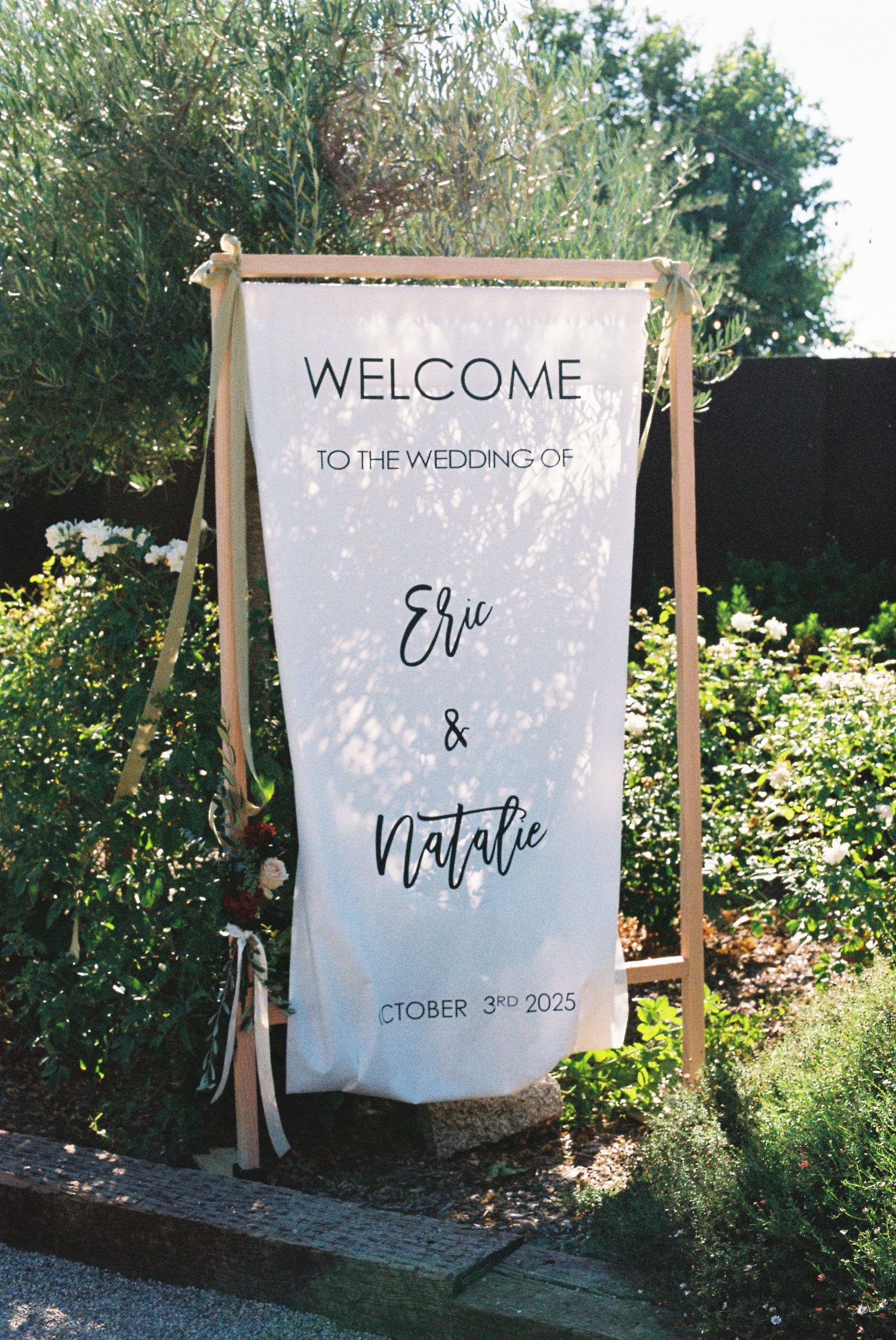 Elegant outdoor wedding welcome sign for Eric and Natalie, October 3rd 2025, on a wooden frame.