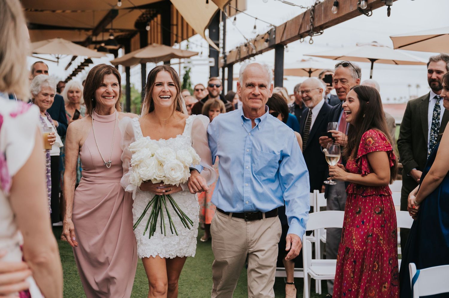 Wedding guests mingle and celebrate during an outdoor reception with string lights overhead.