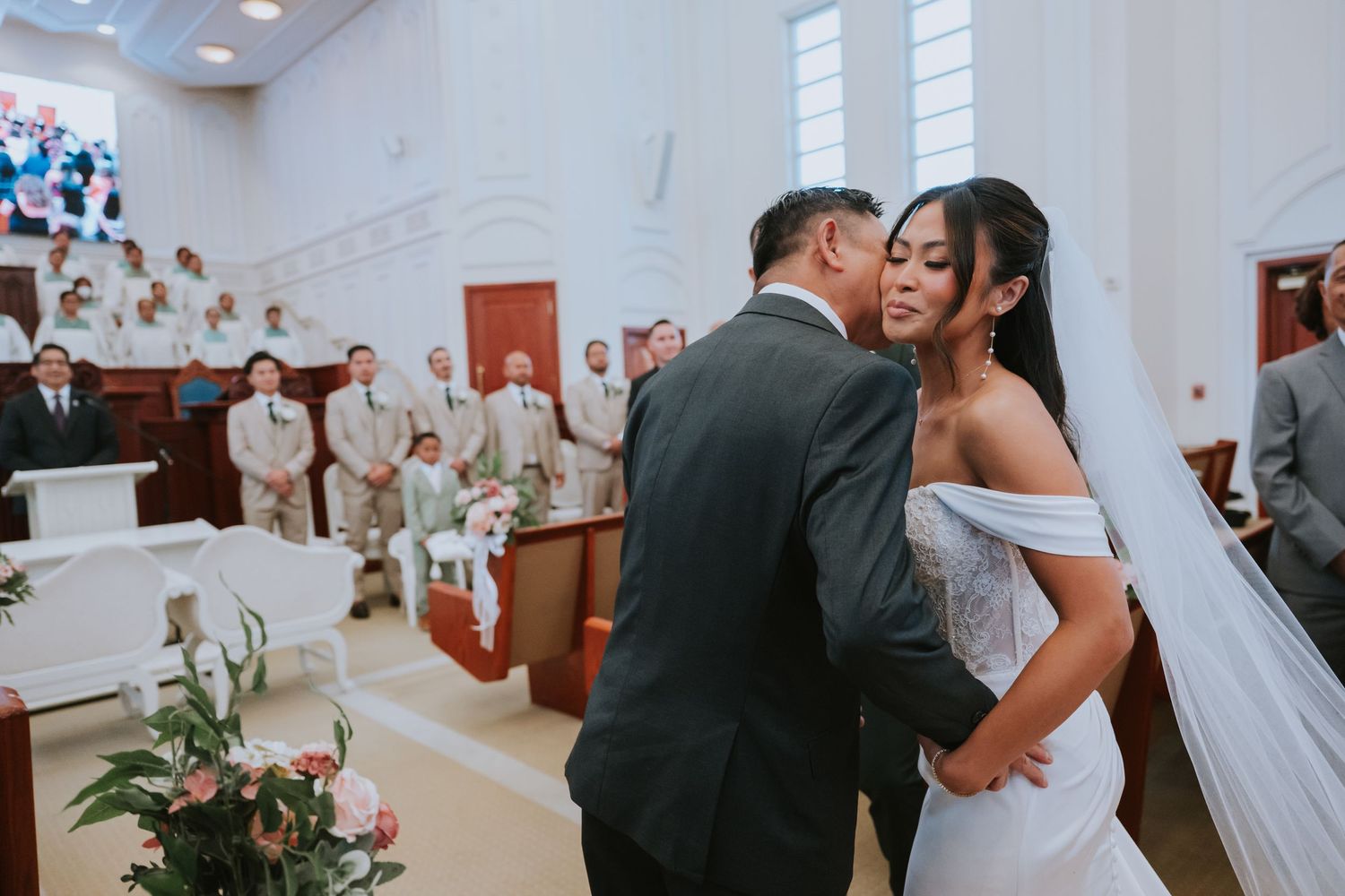 Romantic wedding moments captured in a church setting with white and floral decorations.