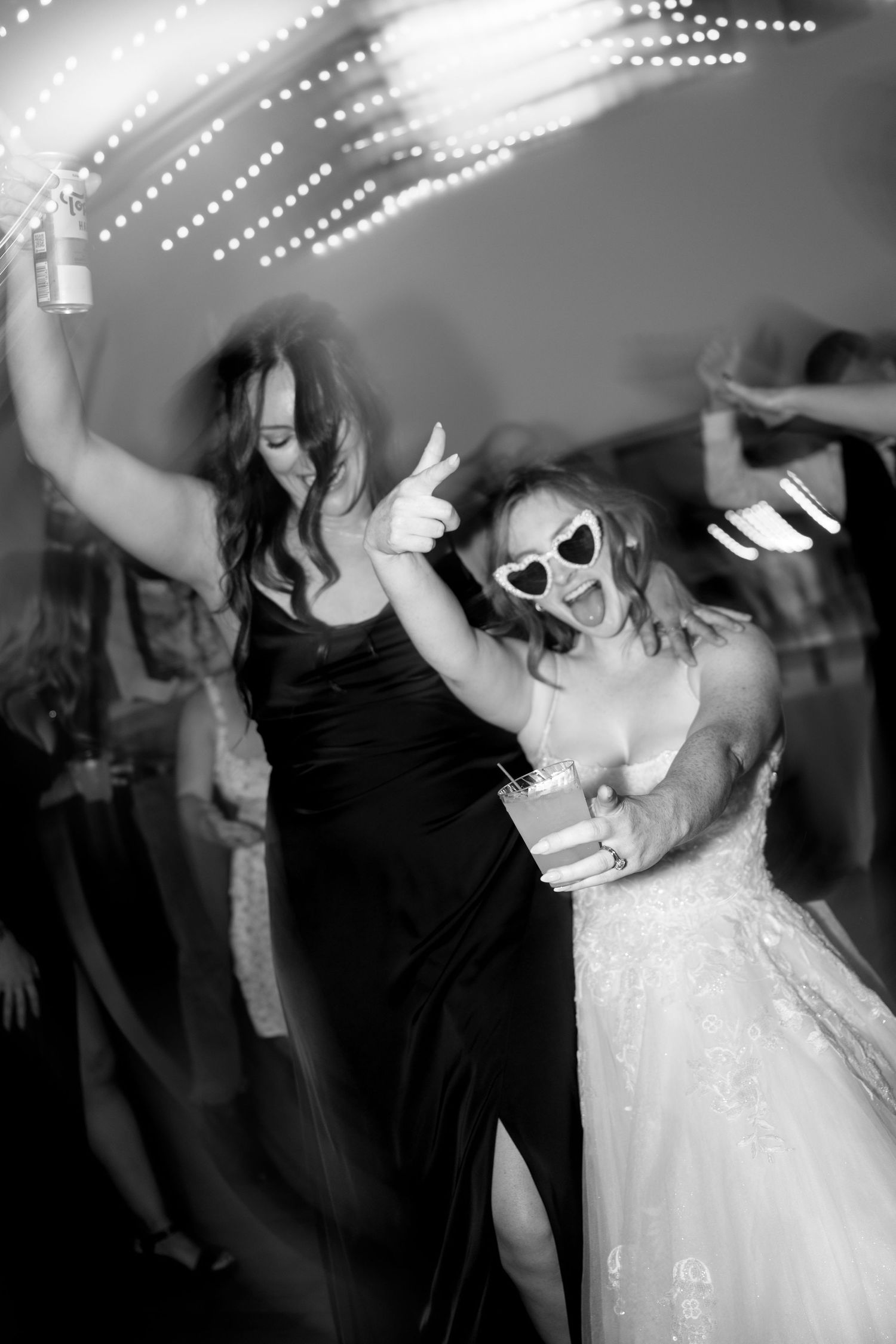 Black and white photos capture joyful dancing at a wedding reception with people in formal attire celebrating on the dance floor.