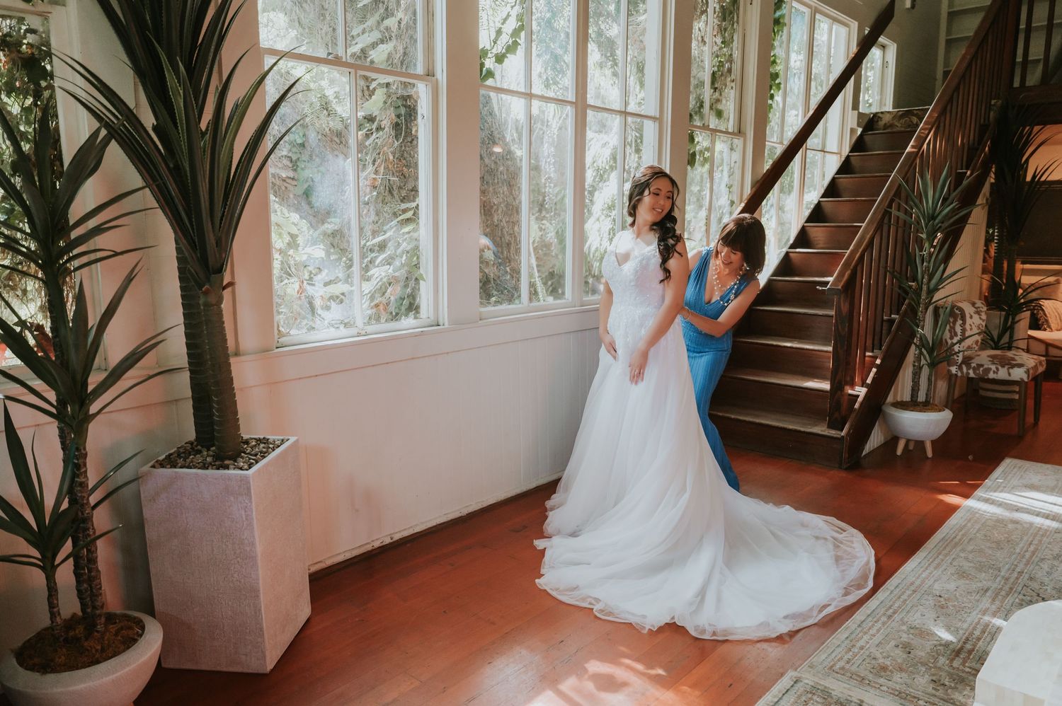 Wedding couple poses on elegant indoor staircase with natural window lighting.