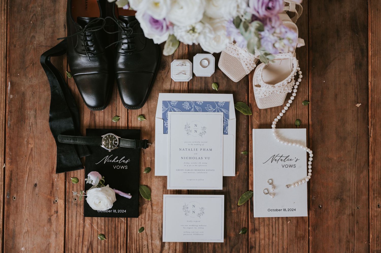 Wedding invitations and decor details arranged on rustic wooden background with floral accents.