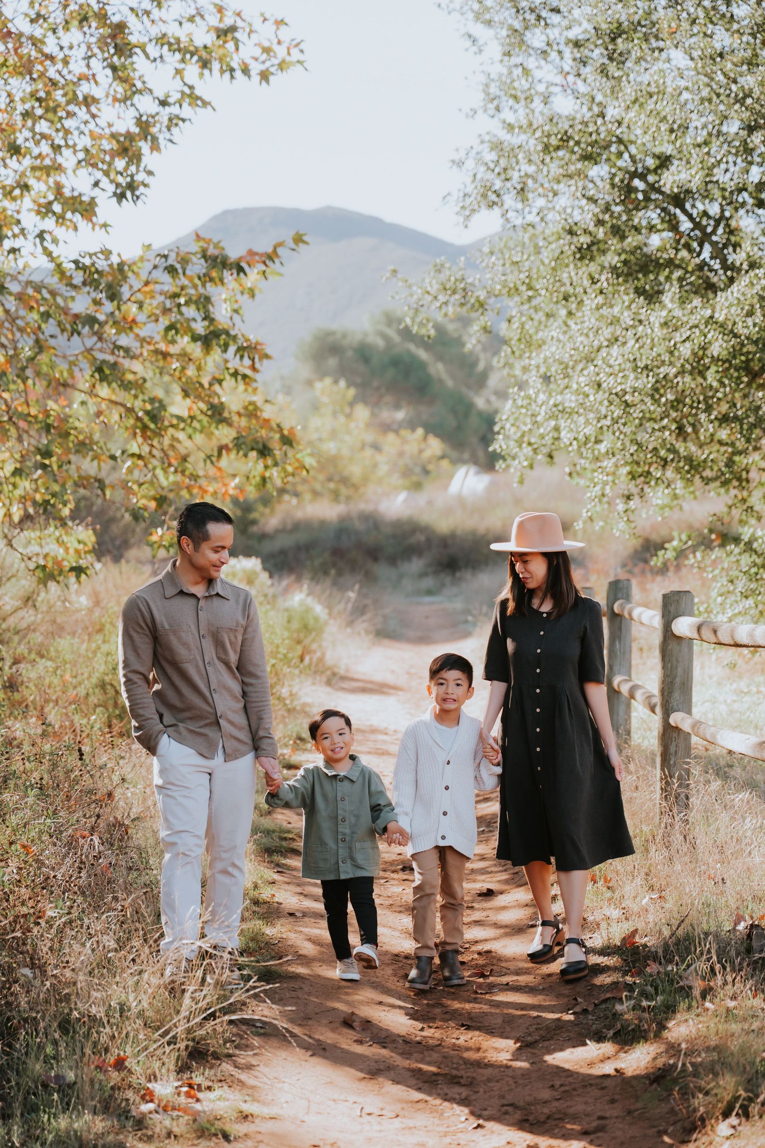 A family walks together on an autumn mountain trail surrounded by golden leaves and natural scenery.