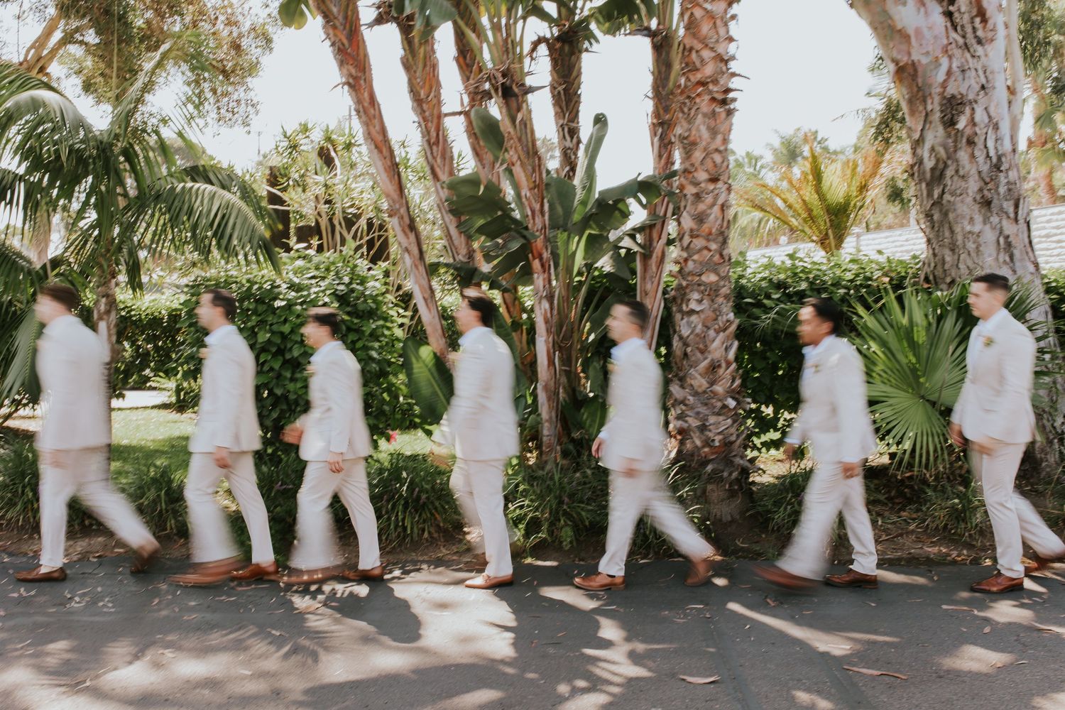 A sequence of wedding party photos showing people in white outfits walking in line through a tropical garden setting.