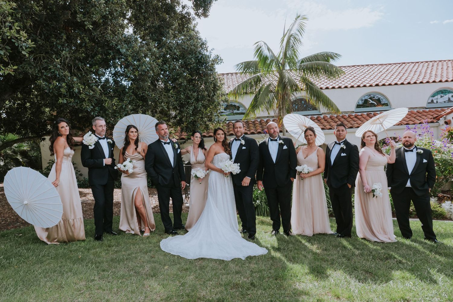 Wedding party poses for formal group photos in a lush garden setting.