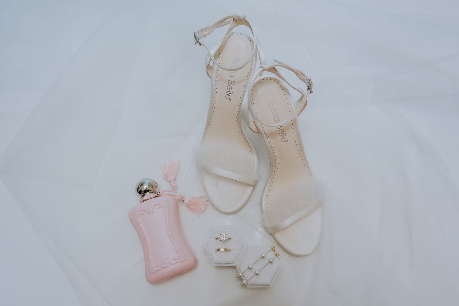 Elegant white bridal shoes with floral embellishments displayed on a light gray background.