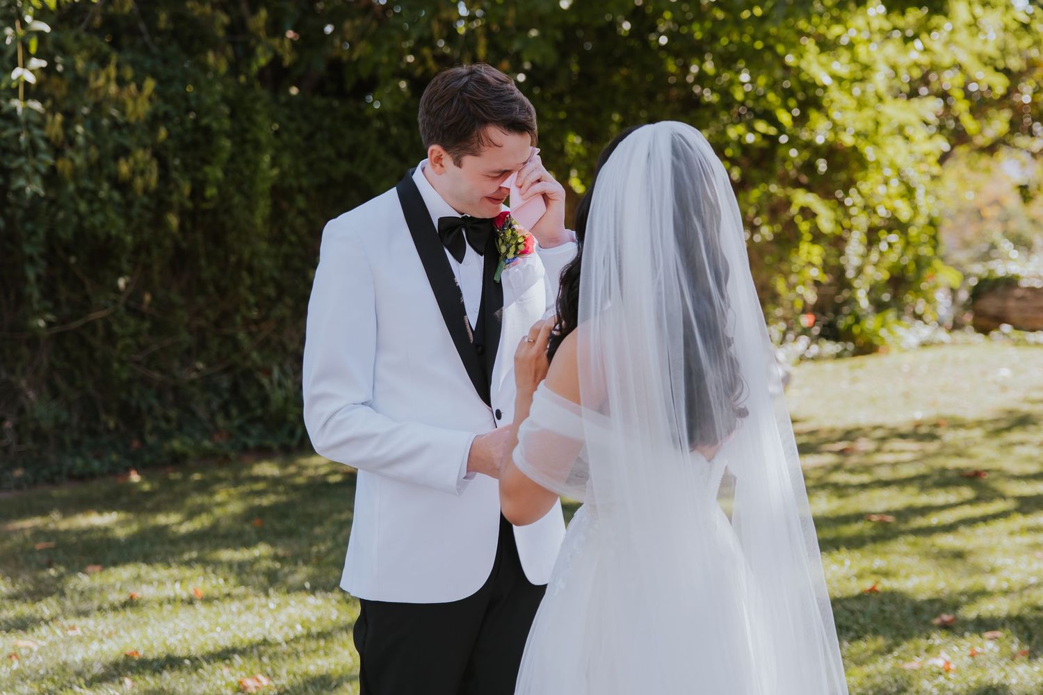 Romantic wedding couple shares tender moments in a sun-dappled garden setting during their autumn celebration.