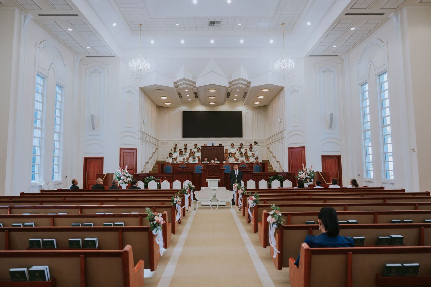 Interior view of a traditional church sanctuary with wooden pews and a choir loft at the altar under bright lighting.
