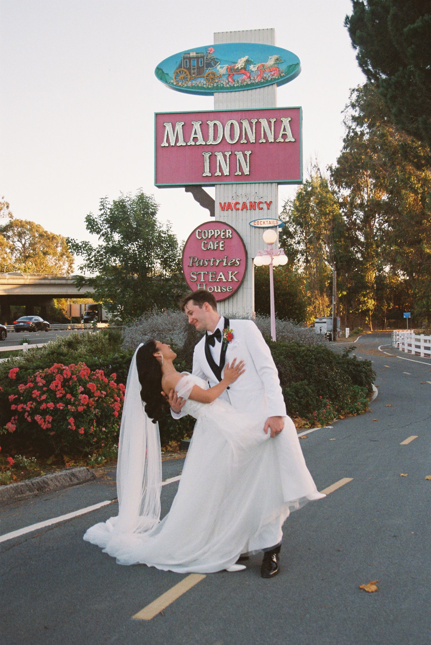Bride and groom share a romantic dip kiss in front of the iconic Madonna Inn sign in San Luis Obispo, CA.