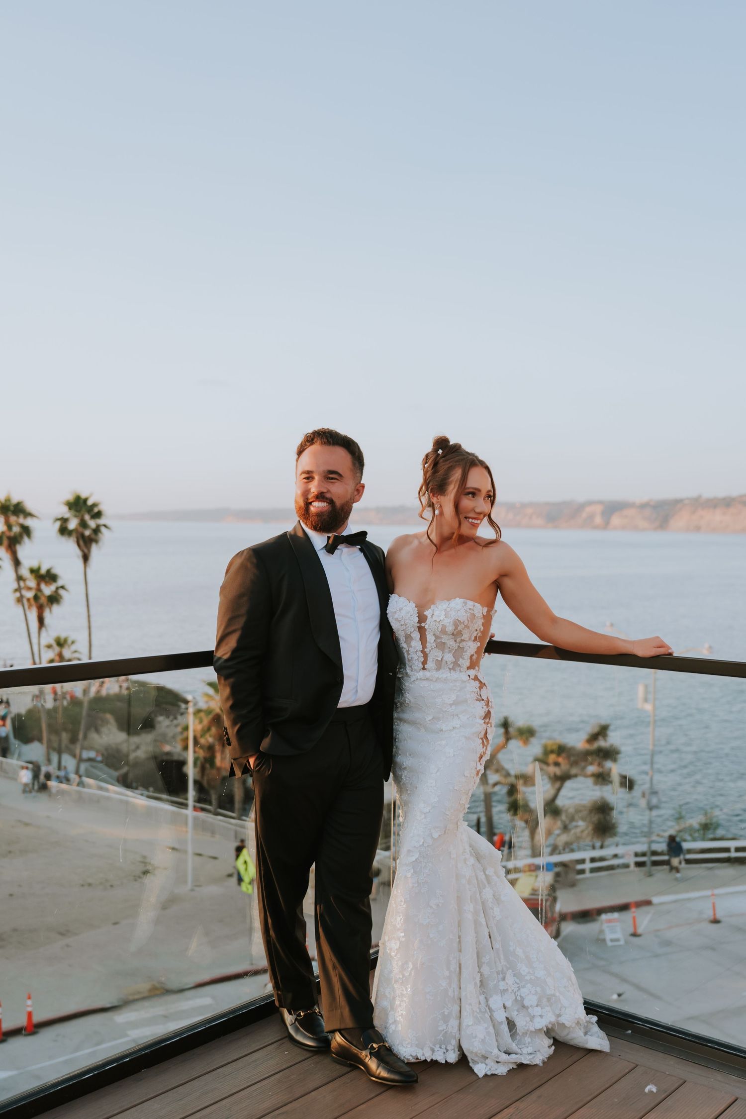 Romantic moment captured on a coastal balcony overlooking the ocean and palm trees.