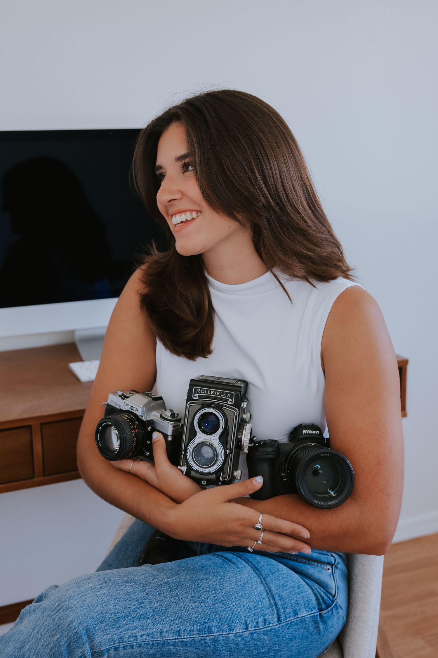 Person holding vintage cameras while sitting in casual attire.
