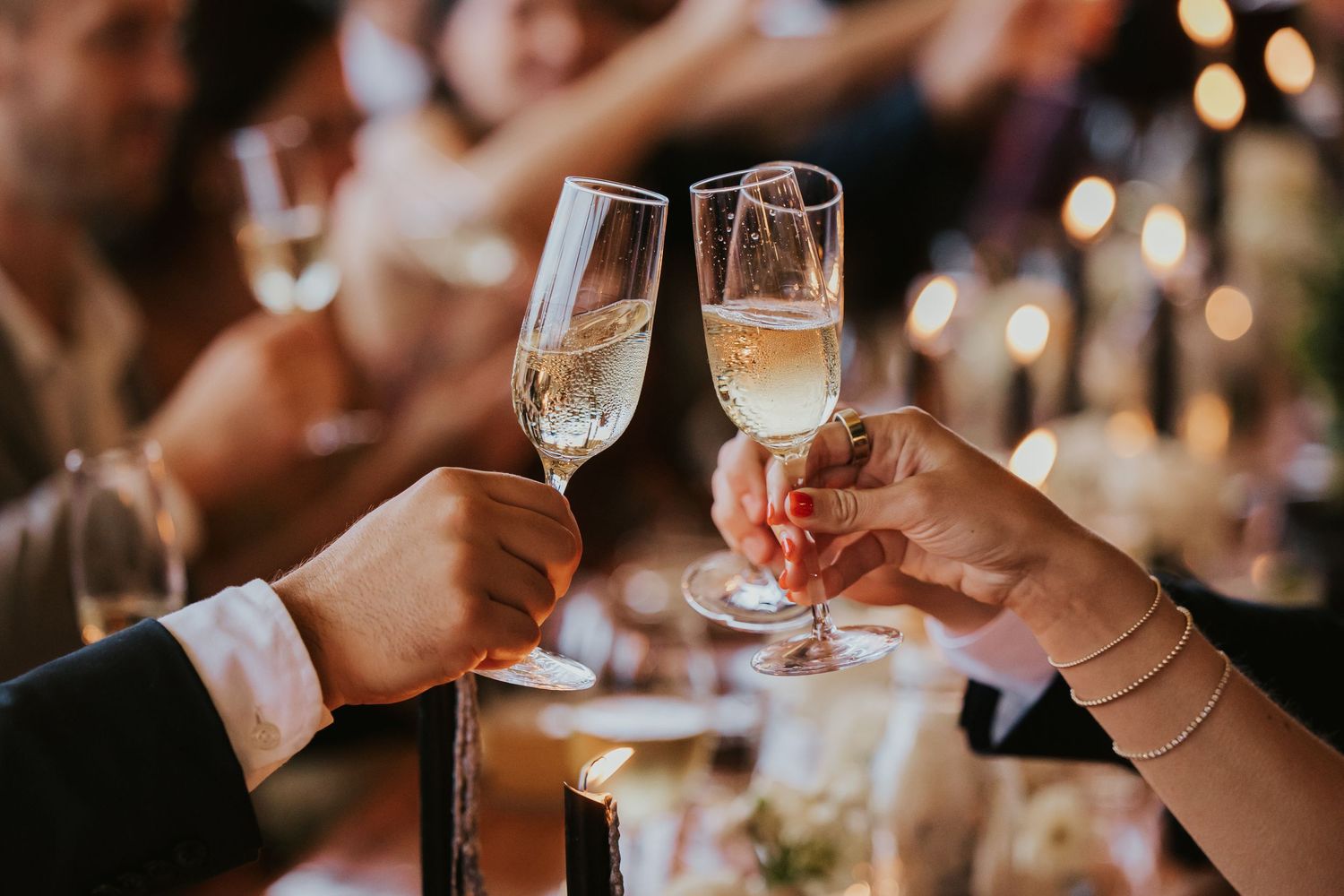 Close-up of hands toasting with wine glasses during an elegant dining celebration.