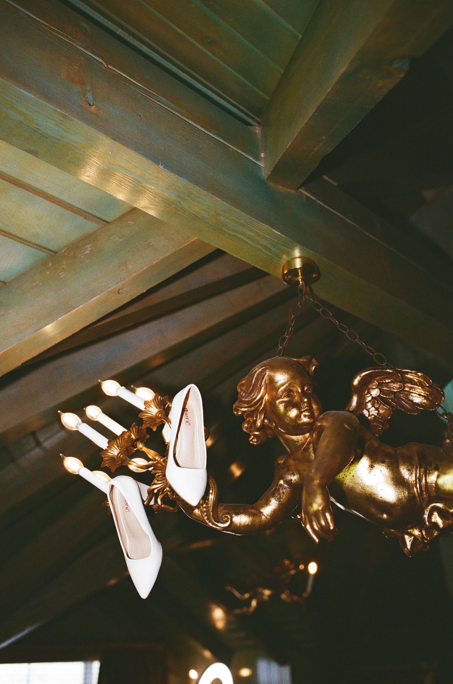 Vintage ornate bronze wall sconces with multiple light fixtures mounted under a green-tinted ceiling.