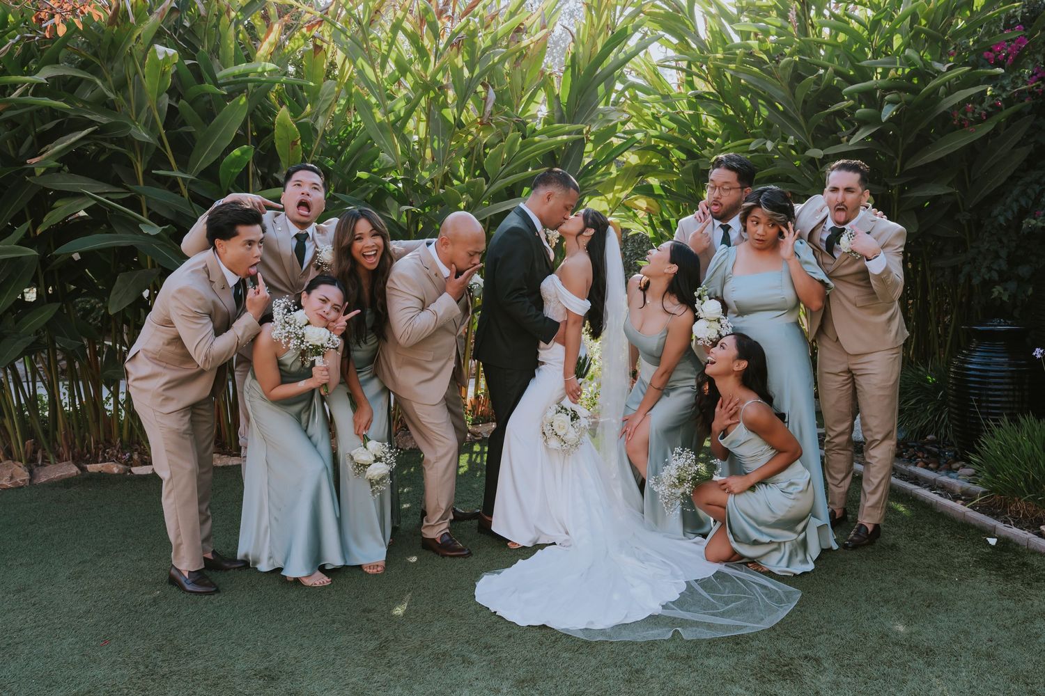 Wedding party in light blue and beige attire poses together for group photos in a lush garden setting.