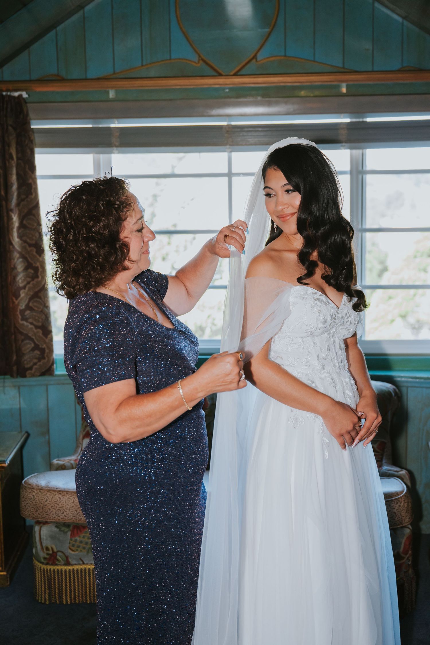 A series of photos showing someone helping to button up a white wedding dress in a sunlit room.