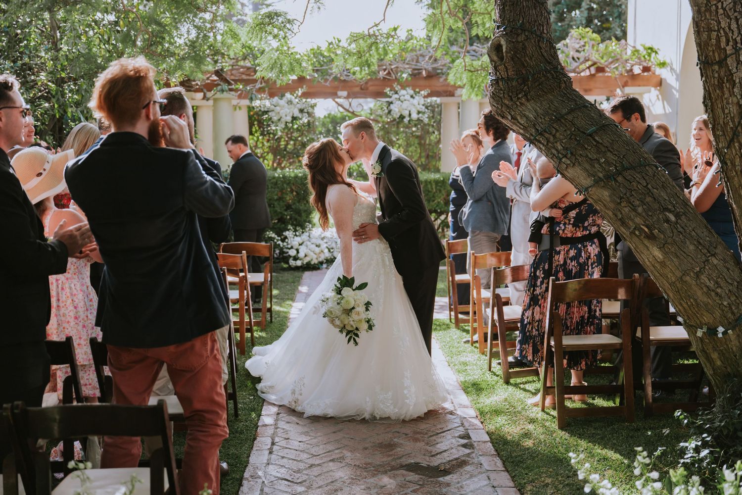 Wedding guests dance and celebrate under a string of outdoor lights at a garden reception party.