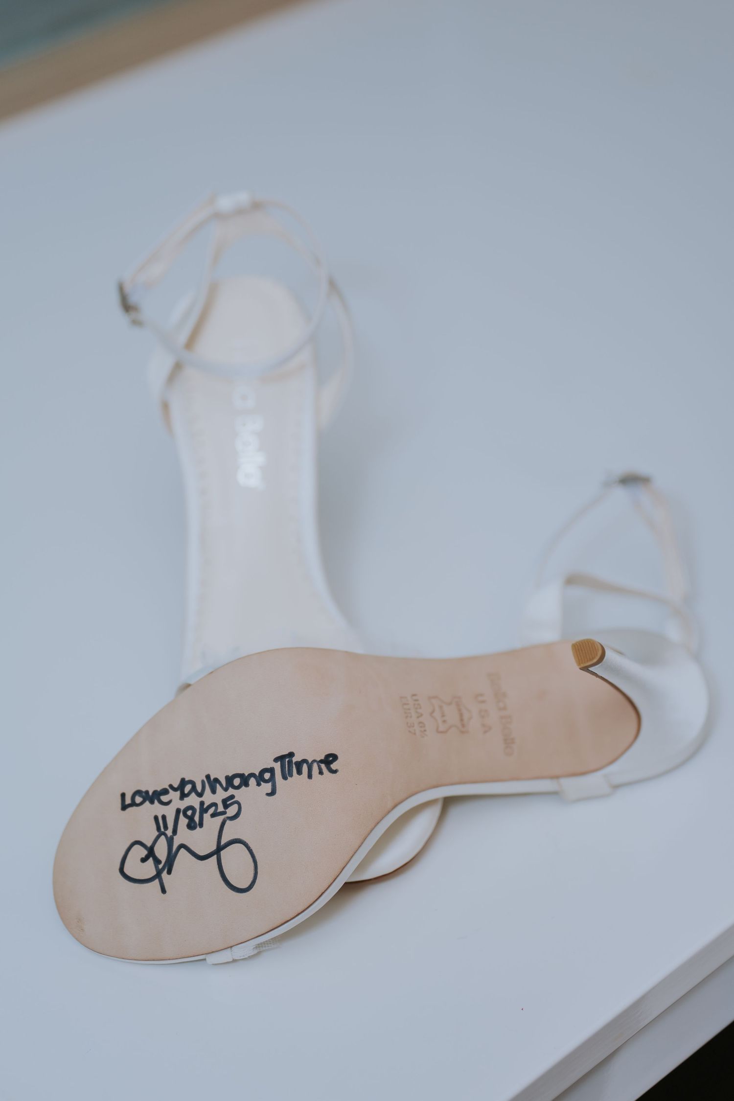 Close-up shots of handwritten text on the soles of white wedding shoes.
