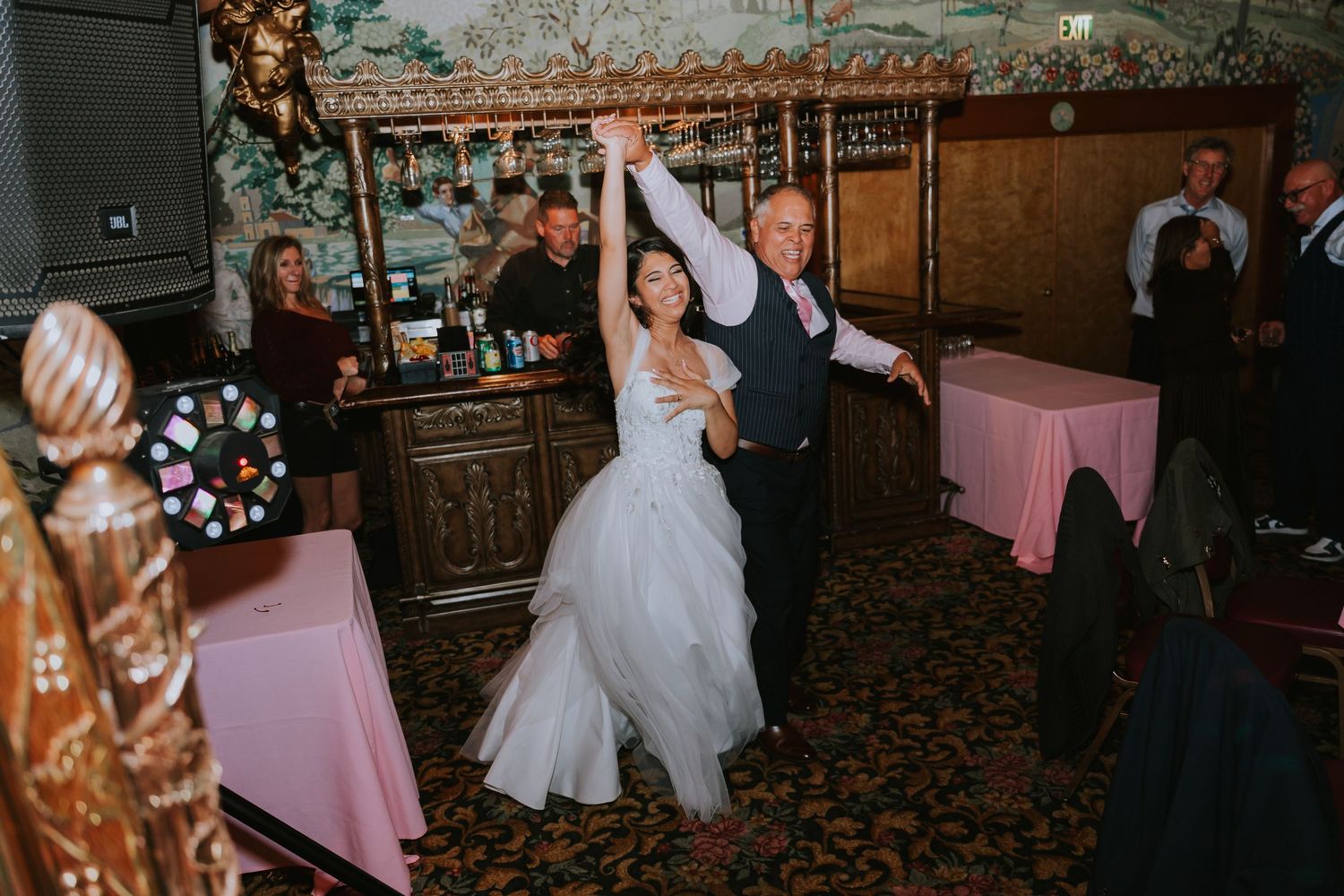Dark and moody wedding reception venue interior with vintage decor and pink tablecloths.