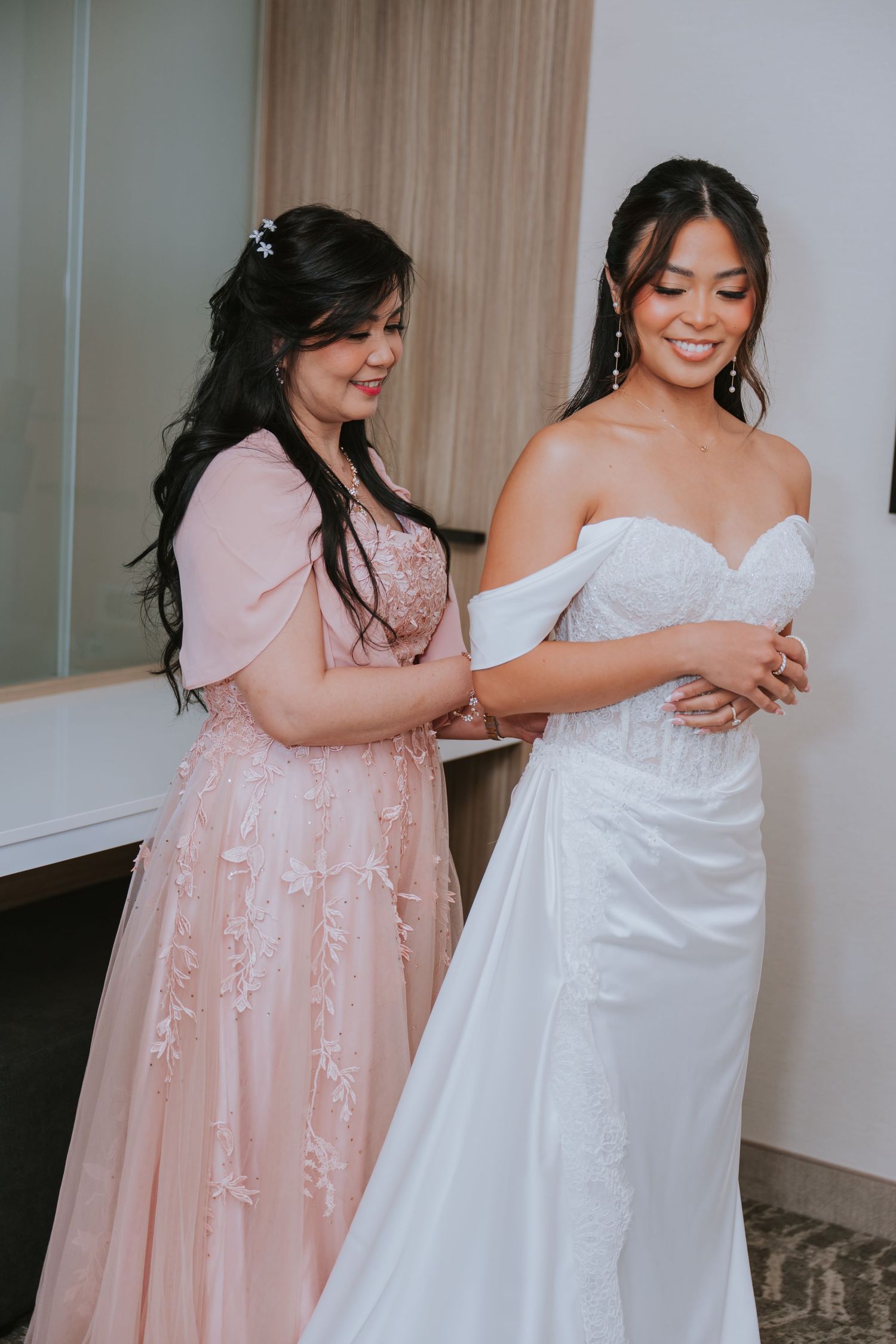 Bridesmaids in pink dresses help adjust a white wedding gown in a series of candid getting-ready moments.