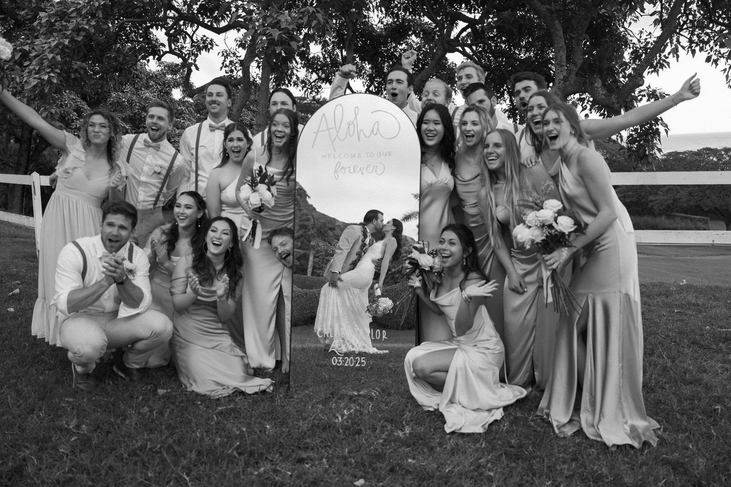 Wedding party poses together outdoors in coordinated gray and lavender dresses and suits.
