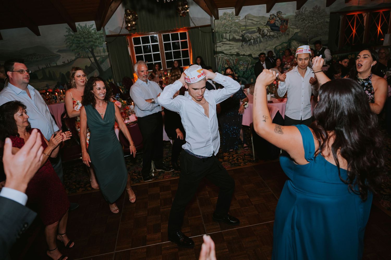 Wedding guests dancing and celebrating at an evening reception with dynamic movement.