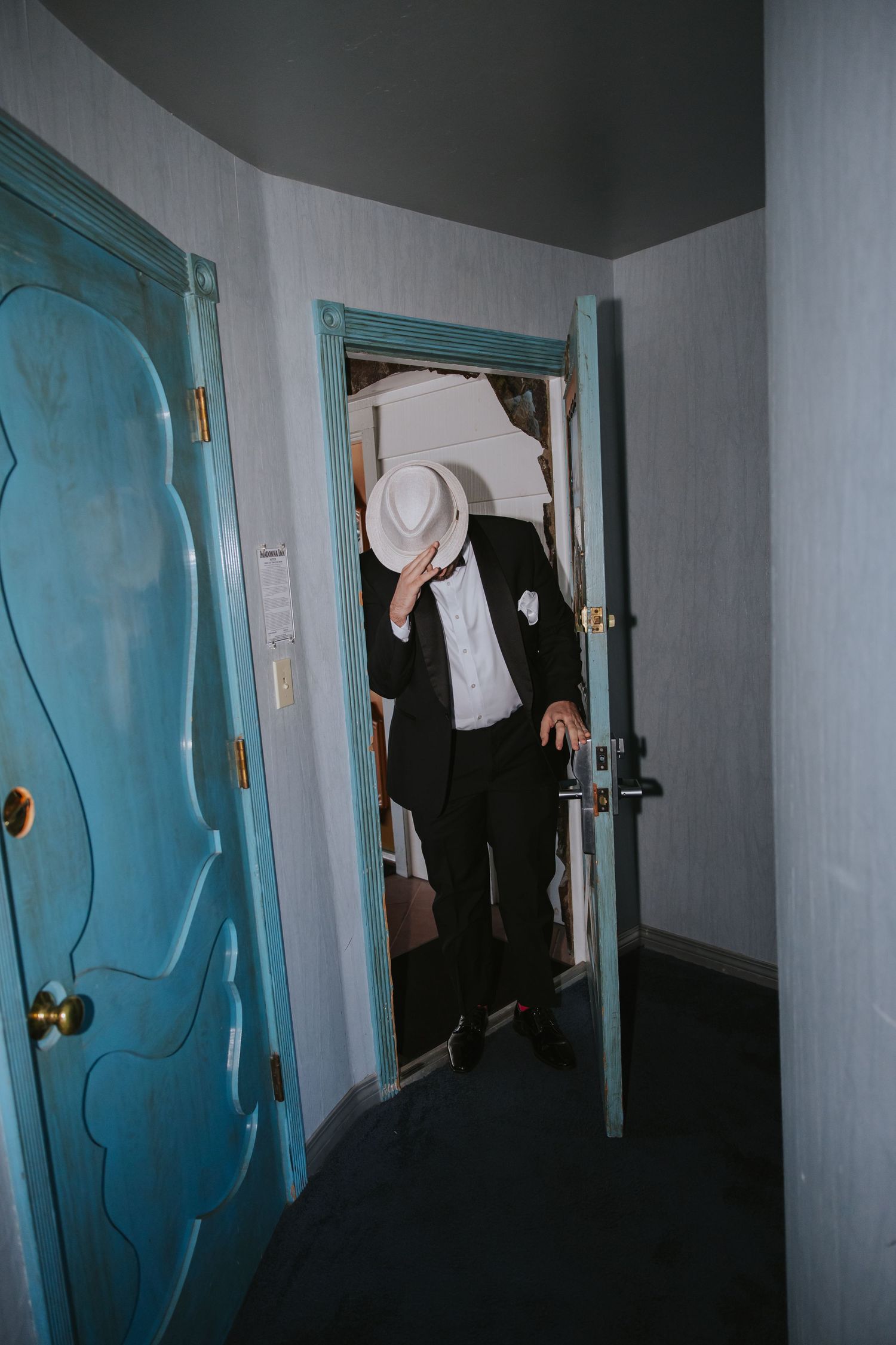 A hallway with turquoise doors and a person walking through, creating a mysterious atmosphere.
