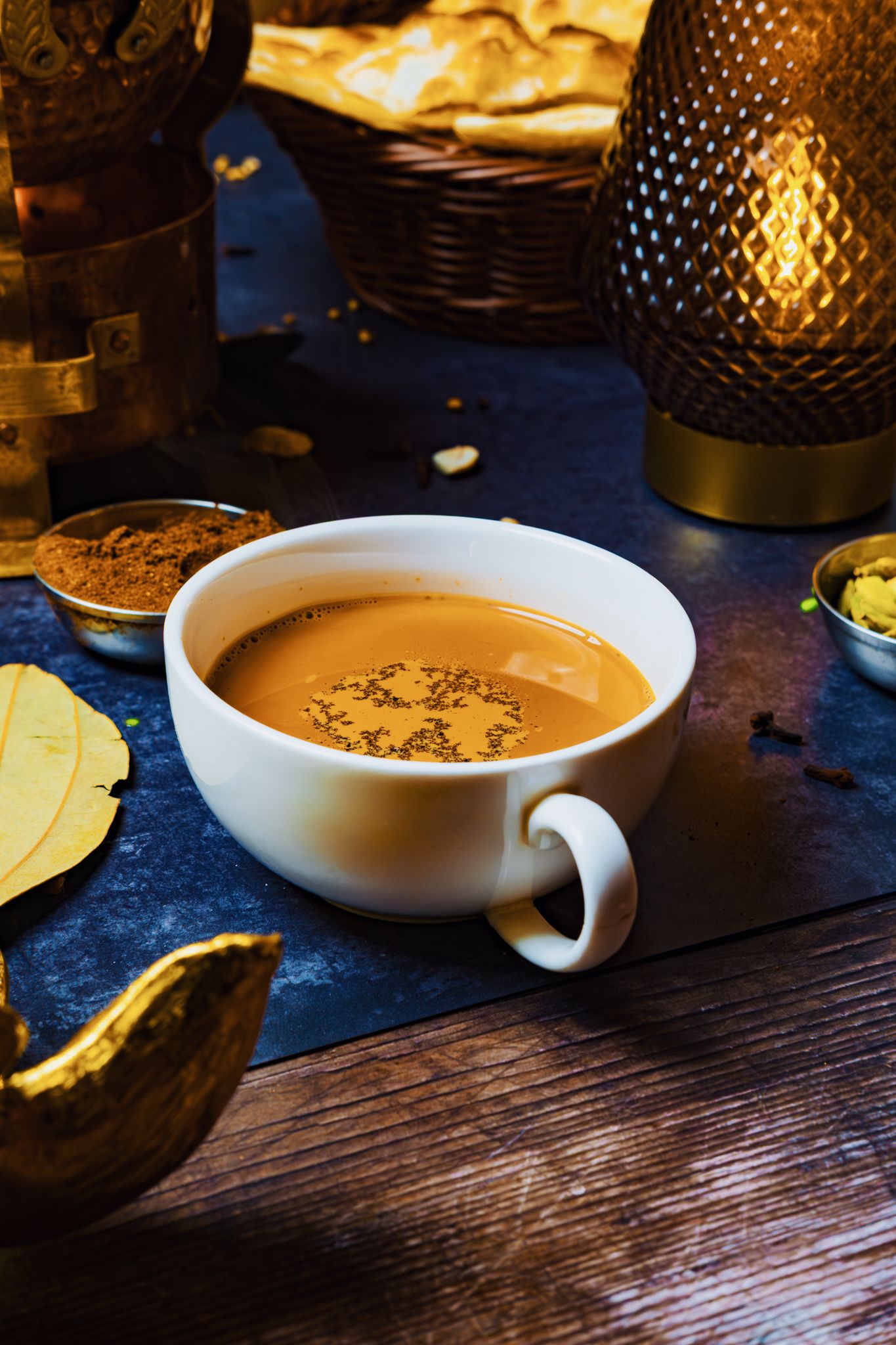 Produktová fotografie. A white cup filled with creamy pumpkin soup garnished with spices on a dark wooden table with ambient lighting.