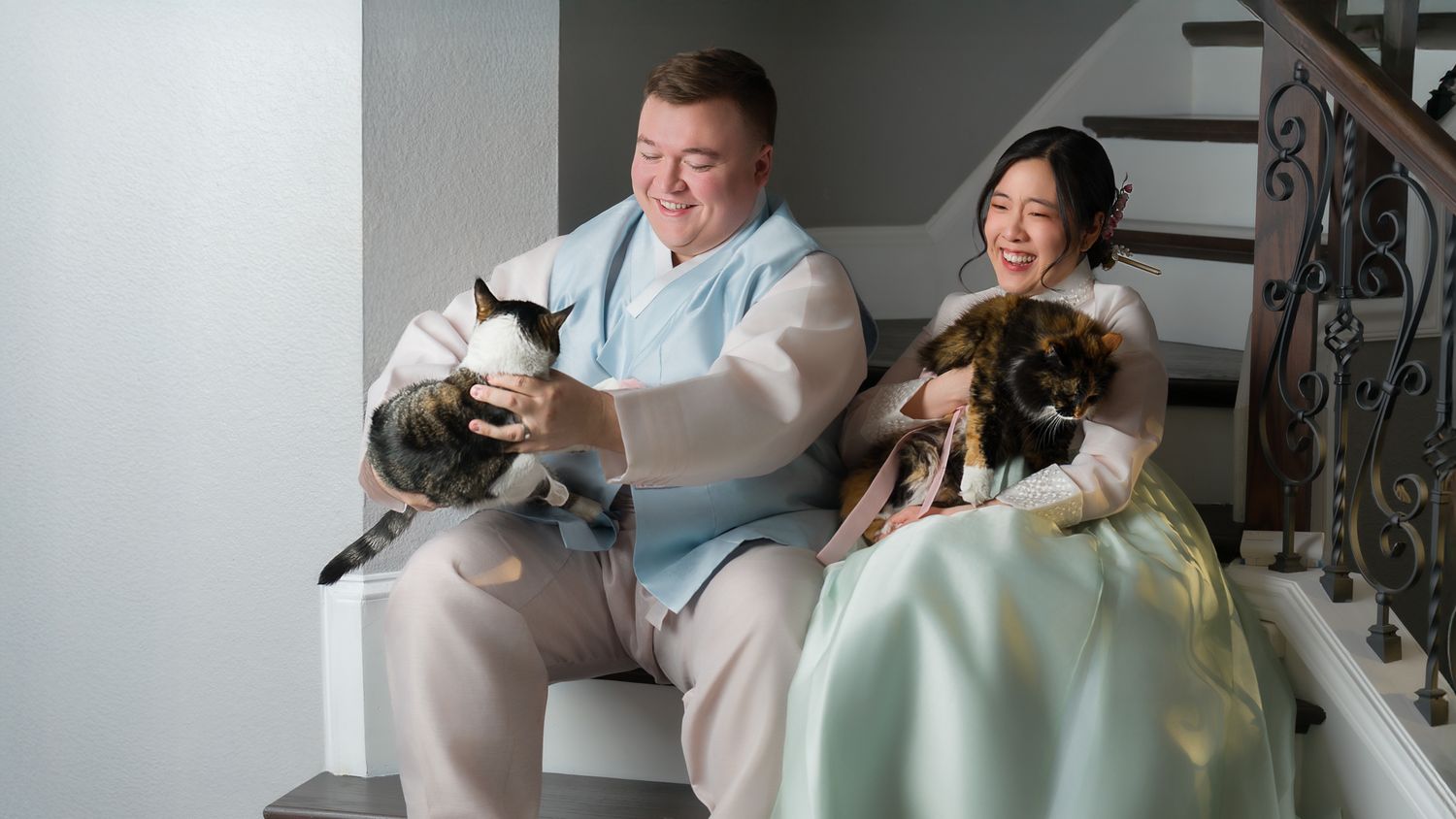 International couple wearing Hanbok, Korean traditional outfit while hold their pet family but the cats not cooperating