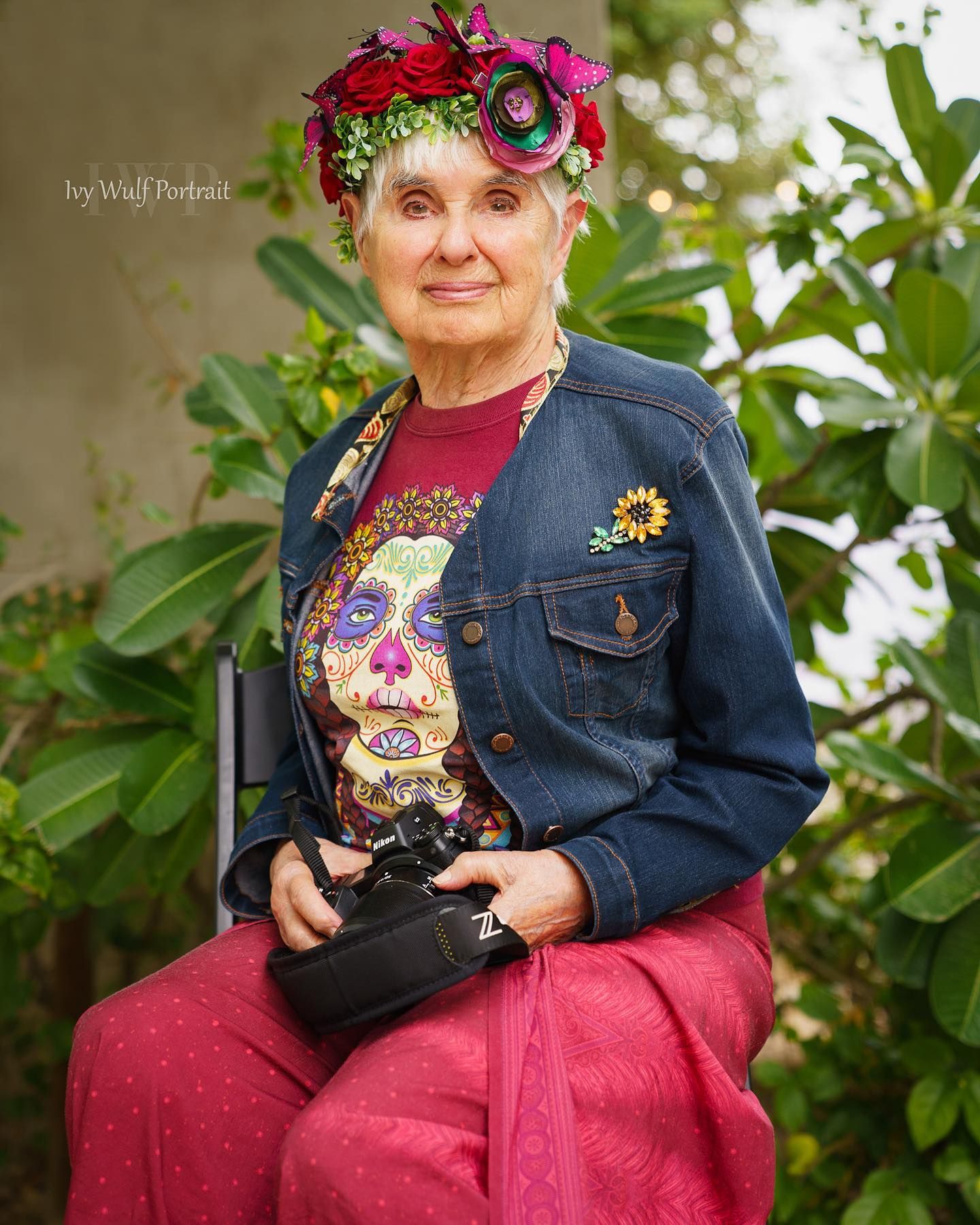 A decade woman photographer portrait wearing colorful flower hair band and holding her camera. Capture in a timeless outdoor.