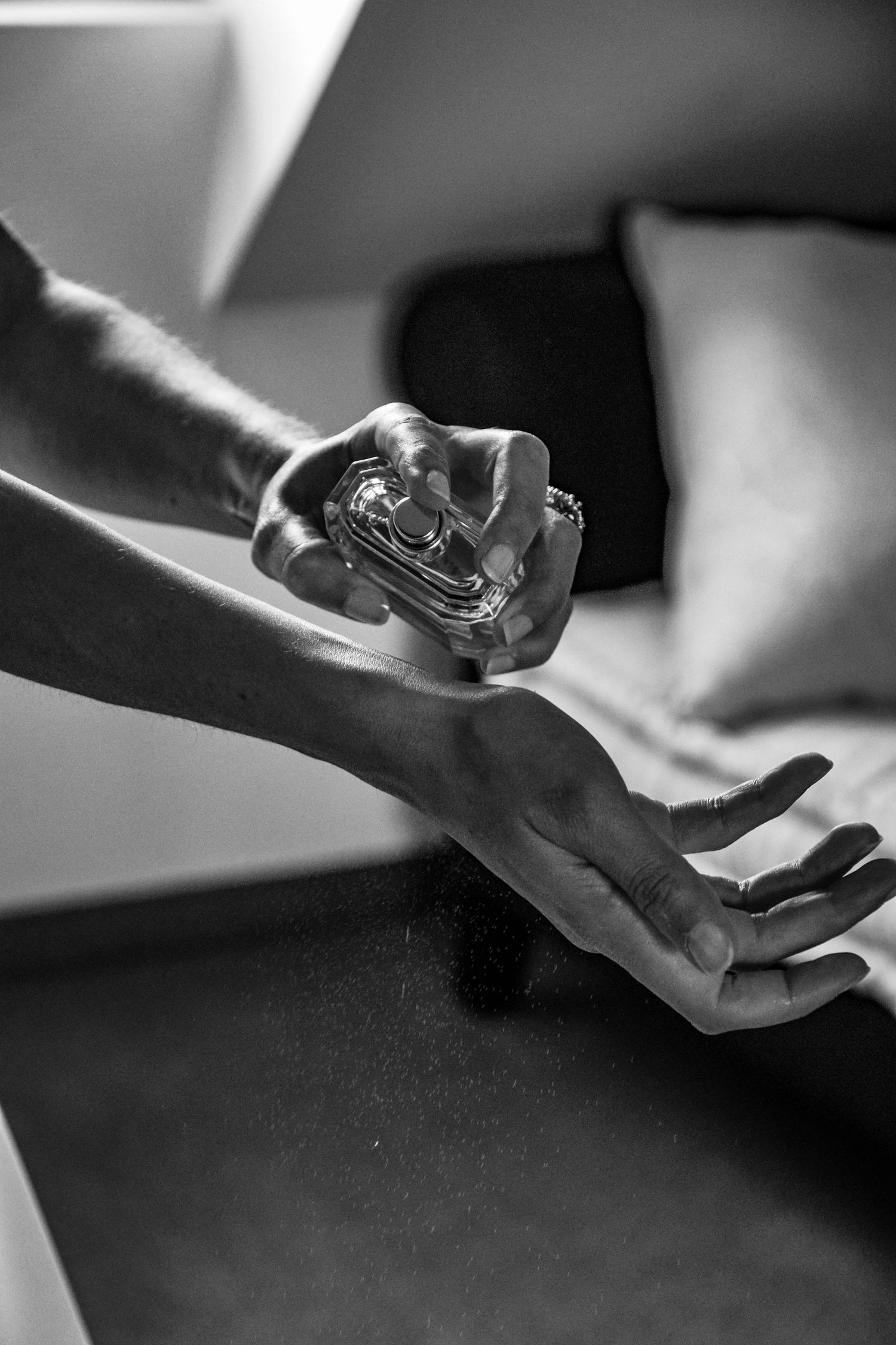 Black and white close-up of perfume being sprayed on wrist.