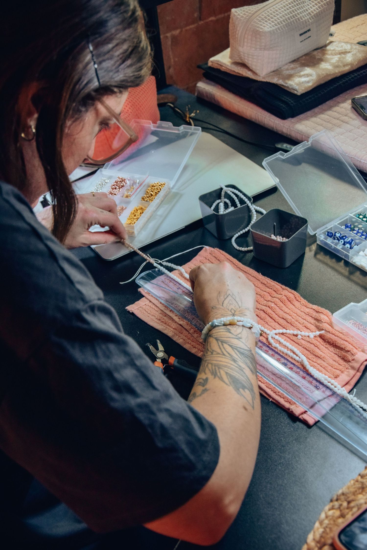 Artisan working on detailed jewelry piece at crafting station with organized supplies.