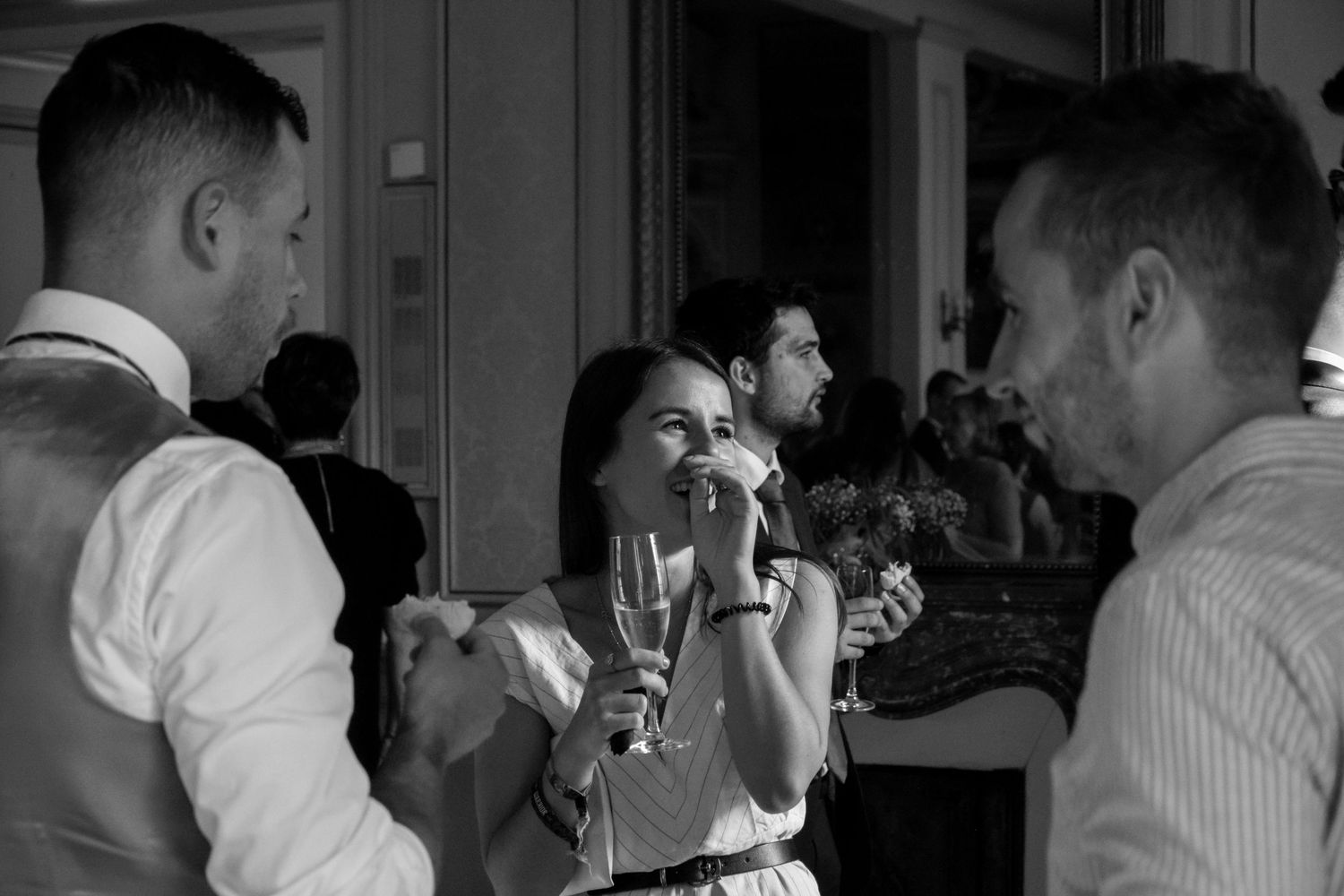 Black and white candid photo of wedding celebration with champagne and laughter.