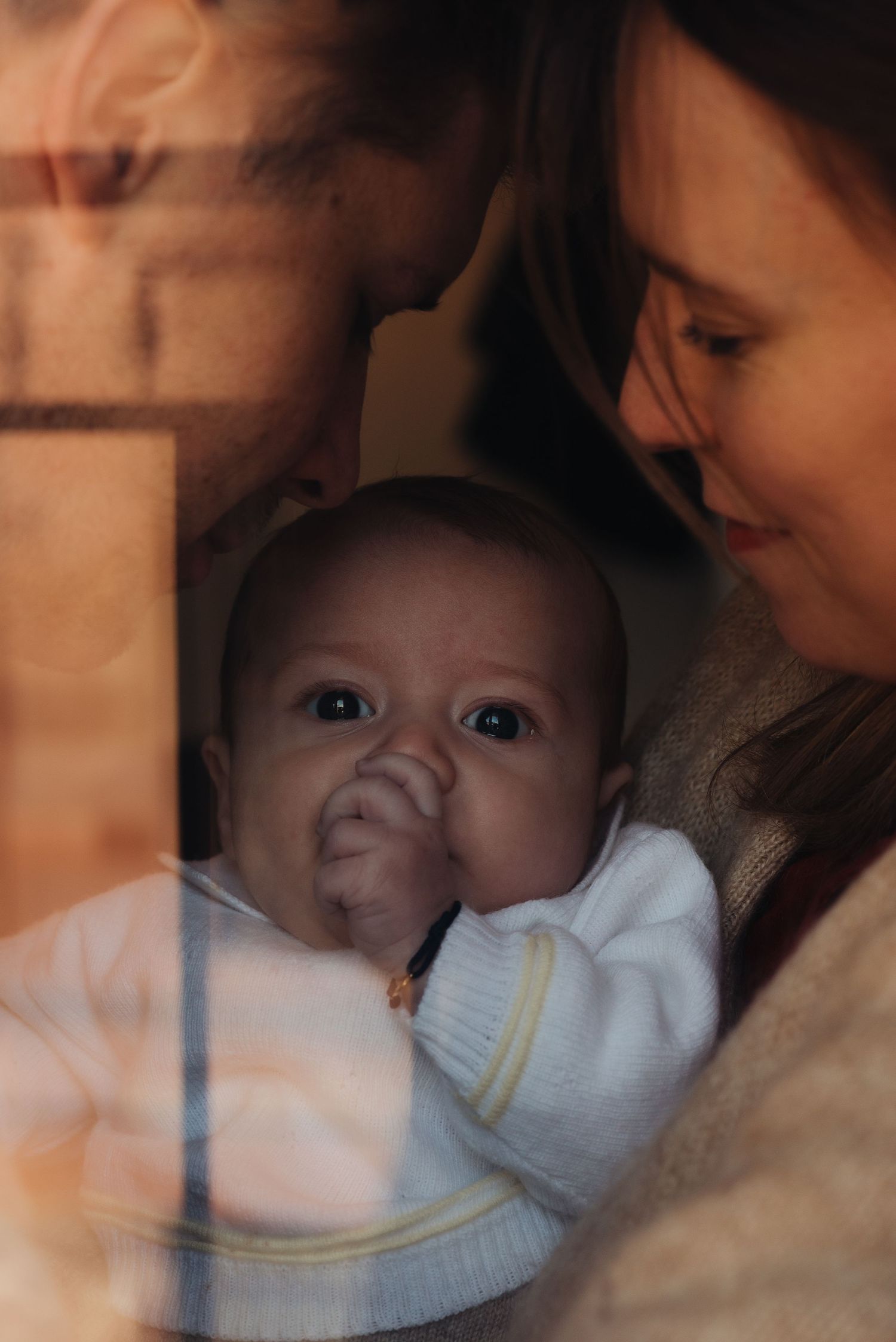 Intimate portrait of an infant and caregiver in warm lighting.