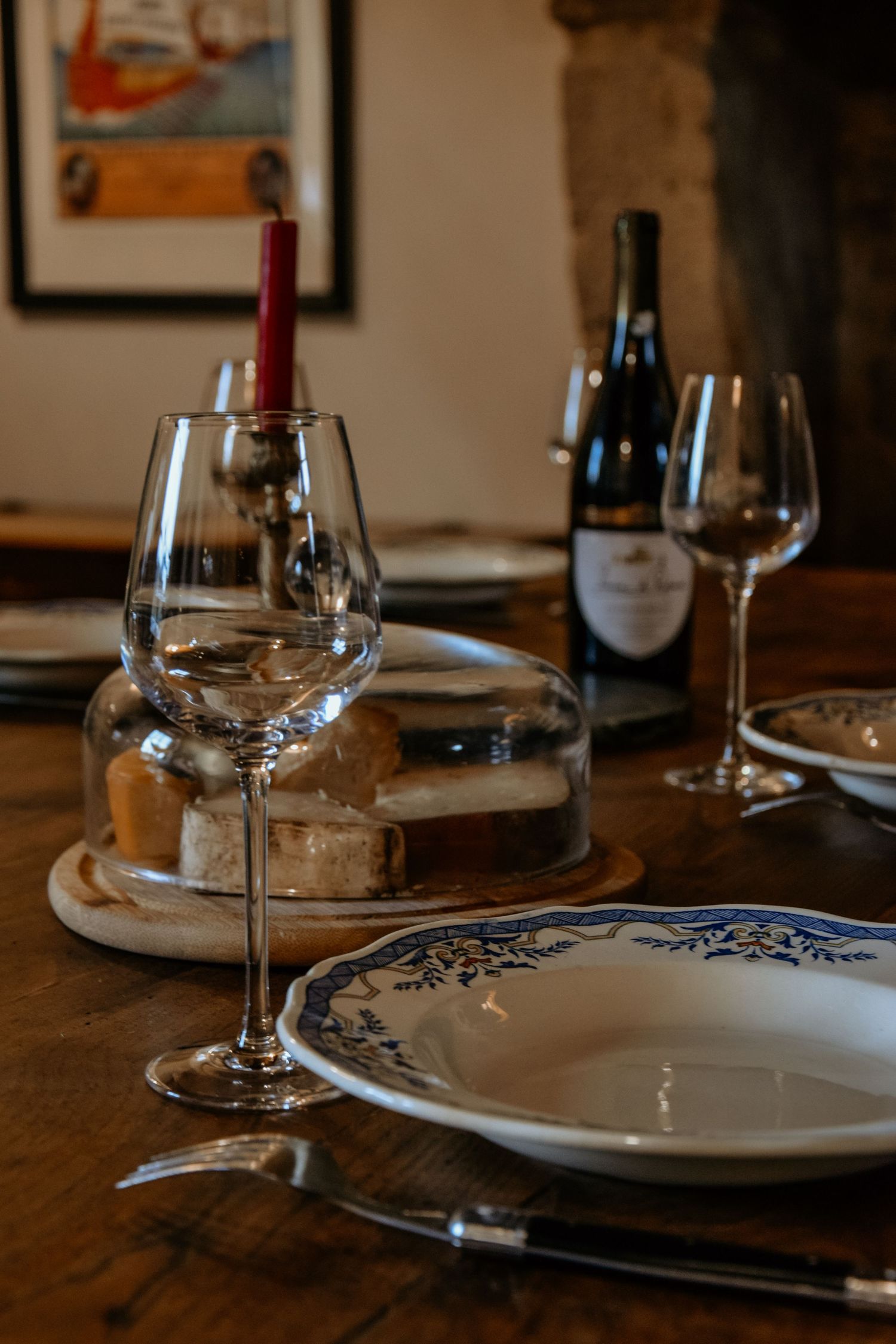 Formal place setting with wine glasses and decorative plates on a rustic wooden table.