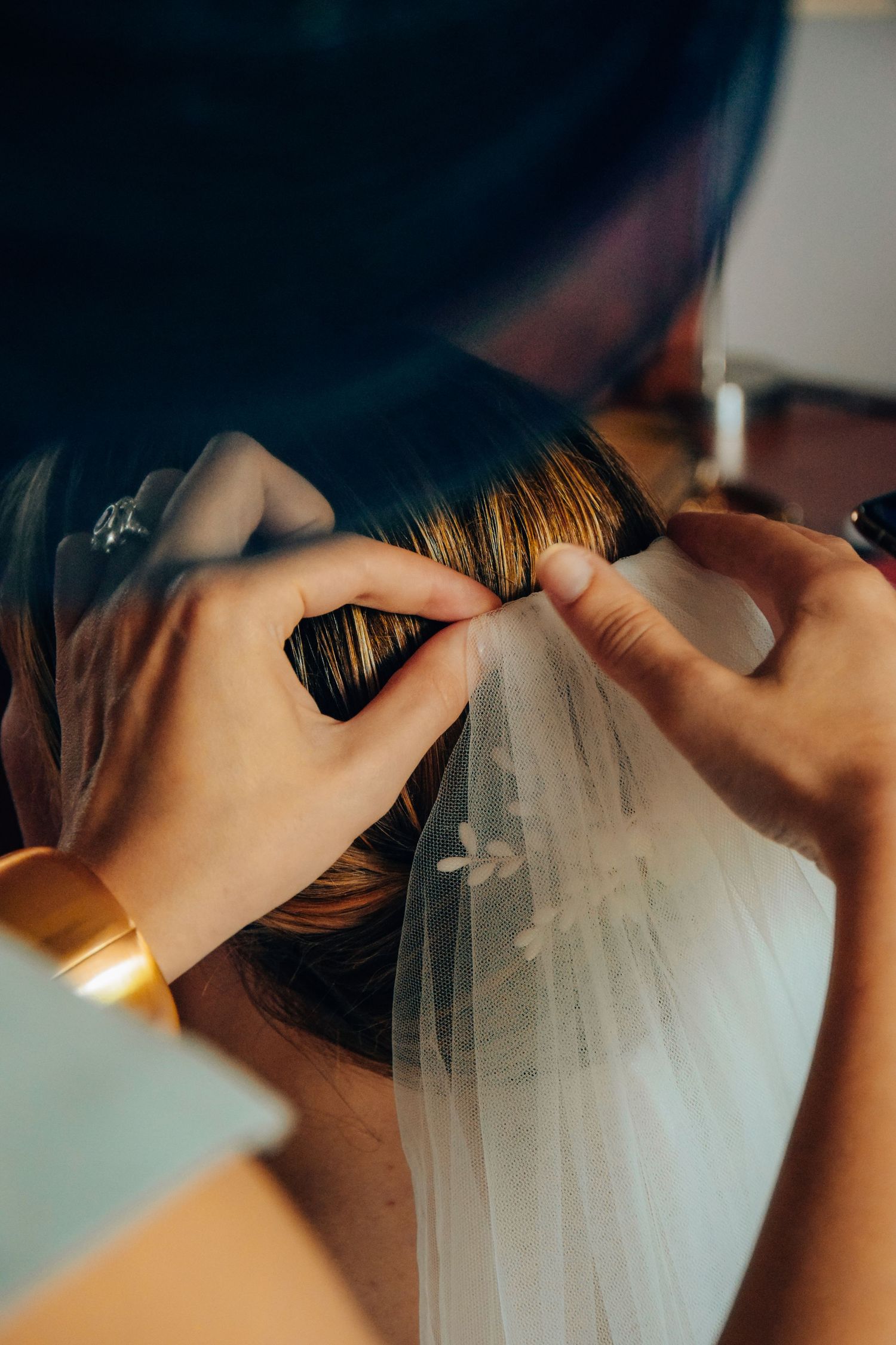 Close-up of hands adjusting bridal veil during wedding preparations.