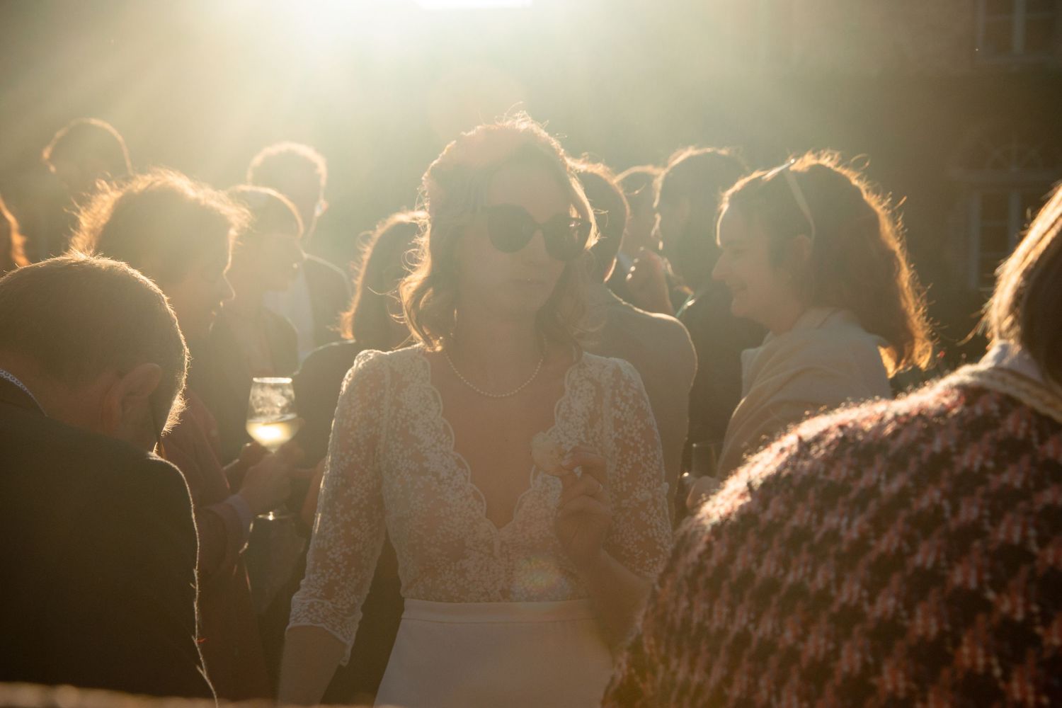 Backlit crowd at an outdoor event with golden sunlight creating silhouettes.