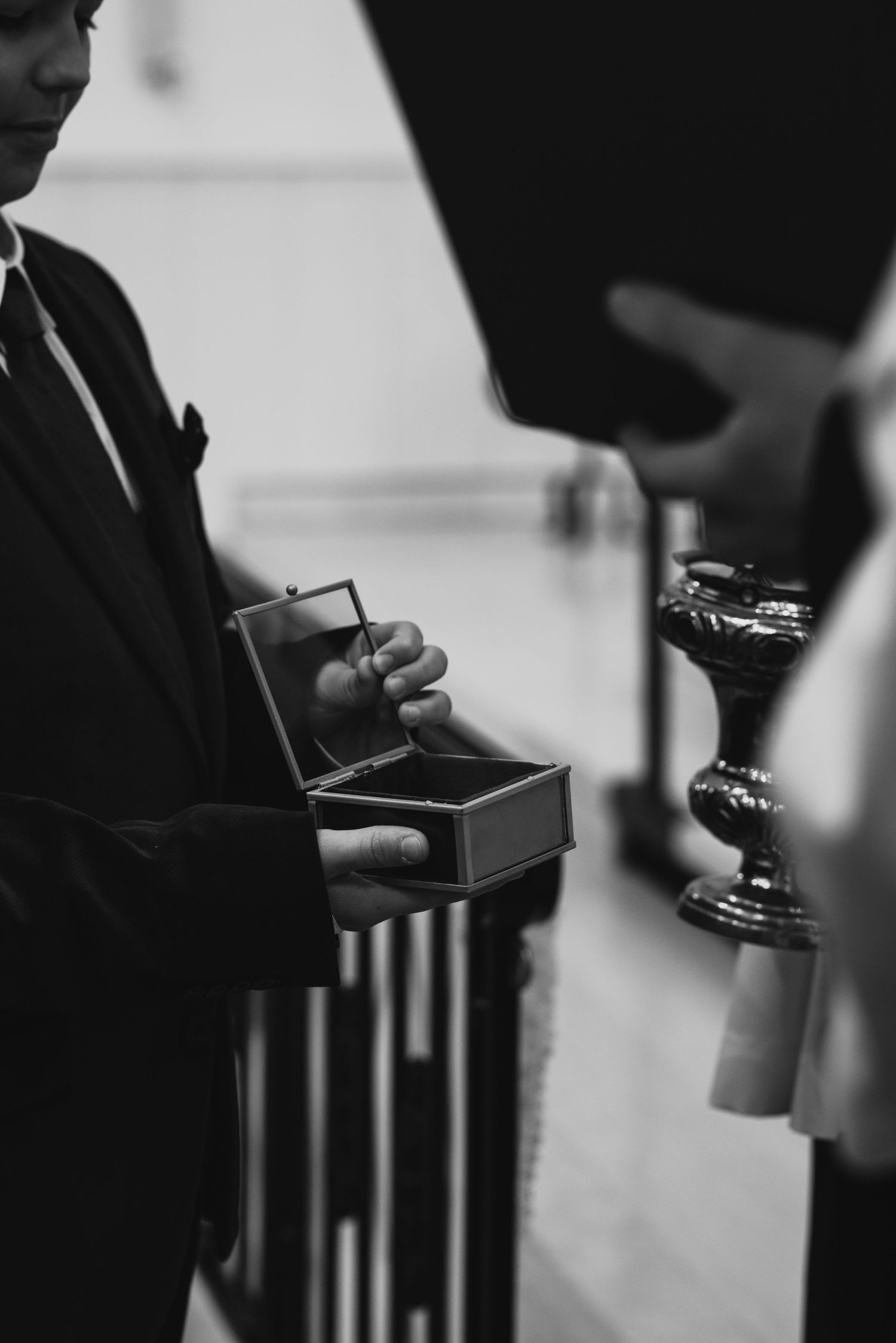 Black and white image of wedding ceremony items being presented in decorative boxes.