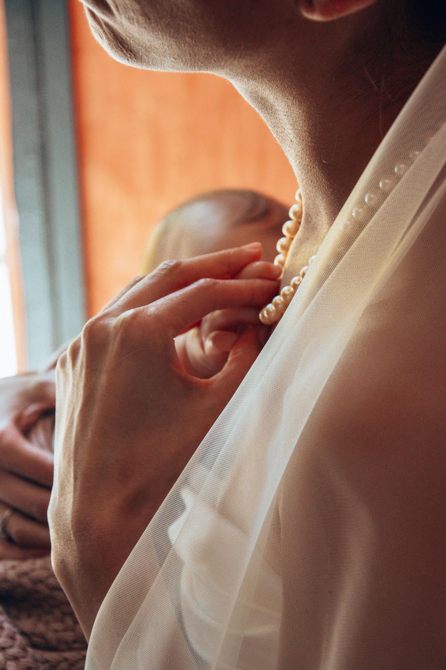 Close-up details of a delicate white wedding dress with intricate pleating and fabric texture in soft lighting.