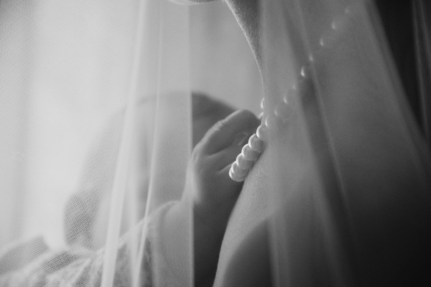 Ethereal black and white photograph showing delicate white fabric veil creating a dreamy, translucent effect.