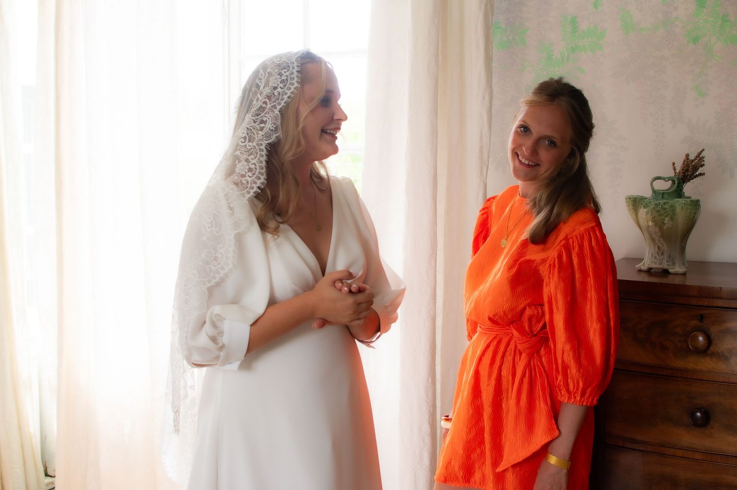 A romantic couple embrace during a wedding photoshoot with the bride wearing white and groom in bright orange attire.
