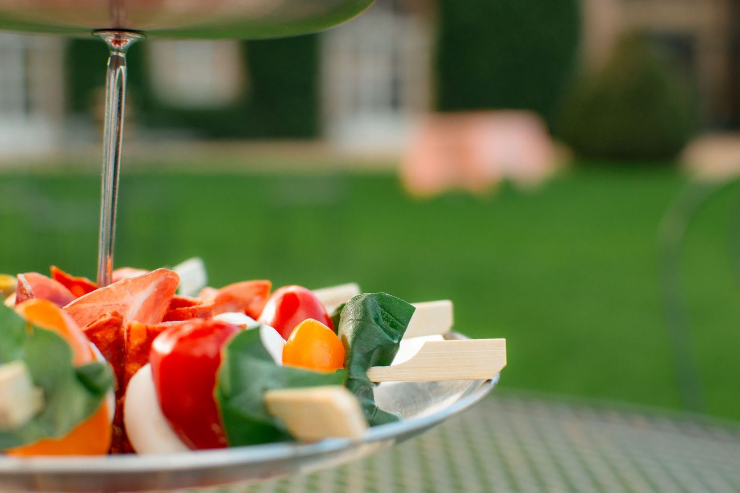 Fresh caprese appetizers with tomatoes, mozzarella and basil on a white plate.