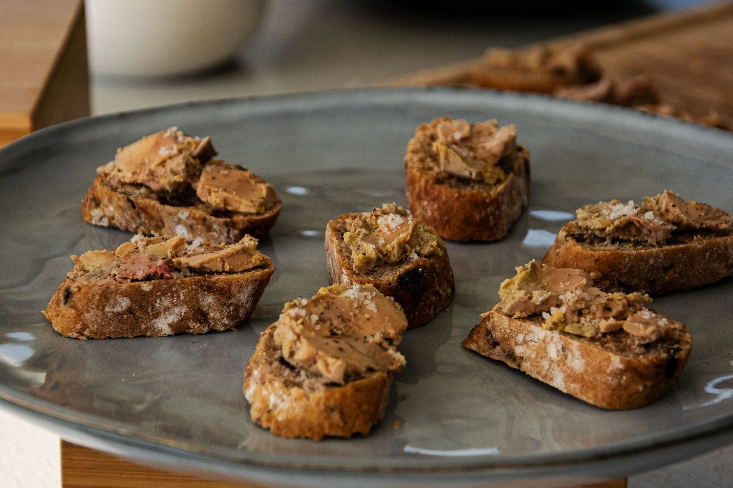 Rustic homemade biscotti cookies with nuts arranged in rows on a dark baking sheet.