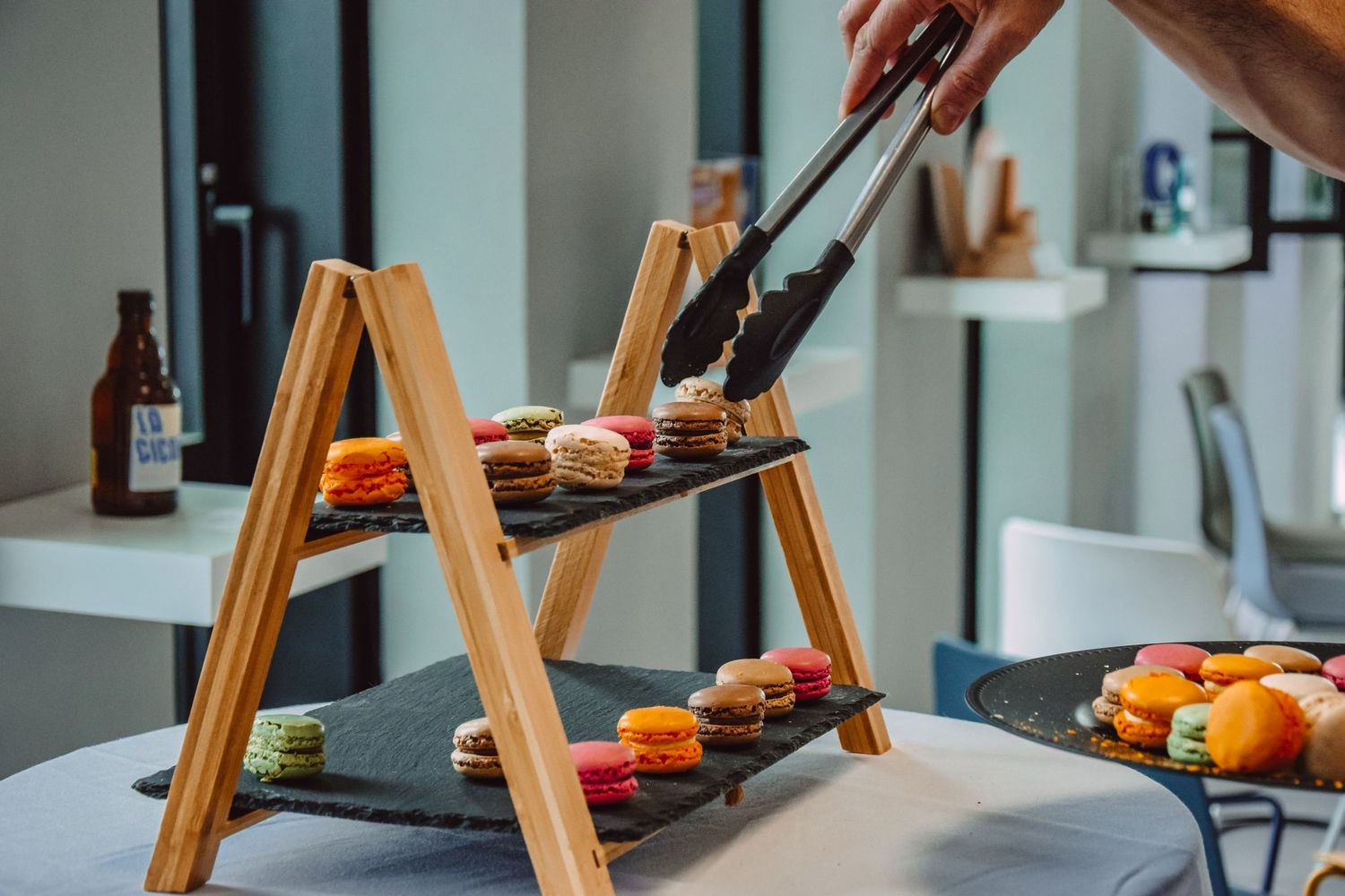 Wooden tiered serving tray displaying appetizers on dark slate plates at an upscale event.