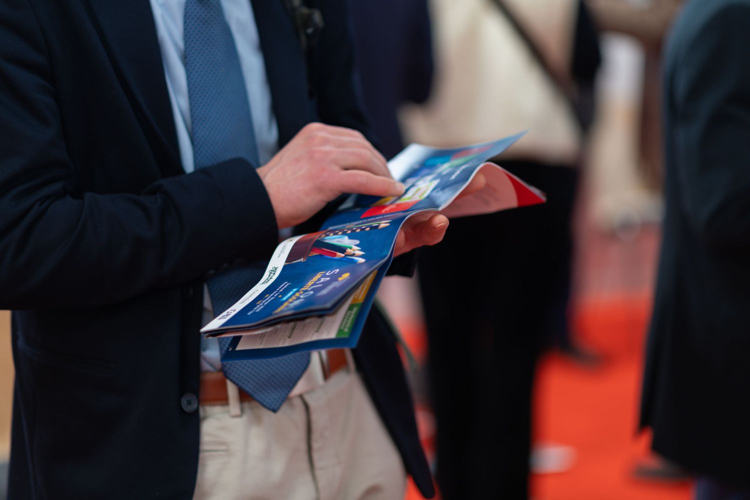 Hands holding blue brochures at formal business gathering.